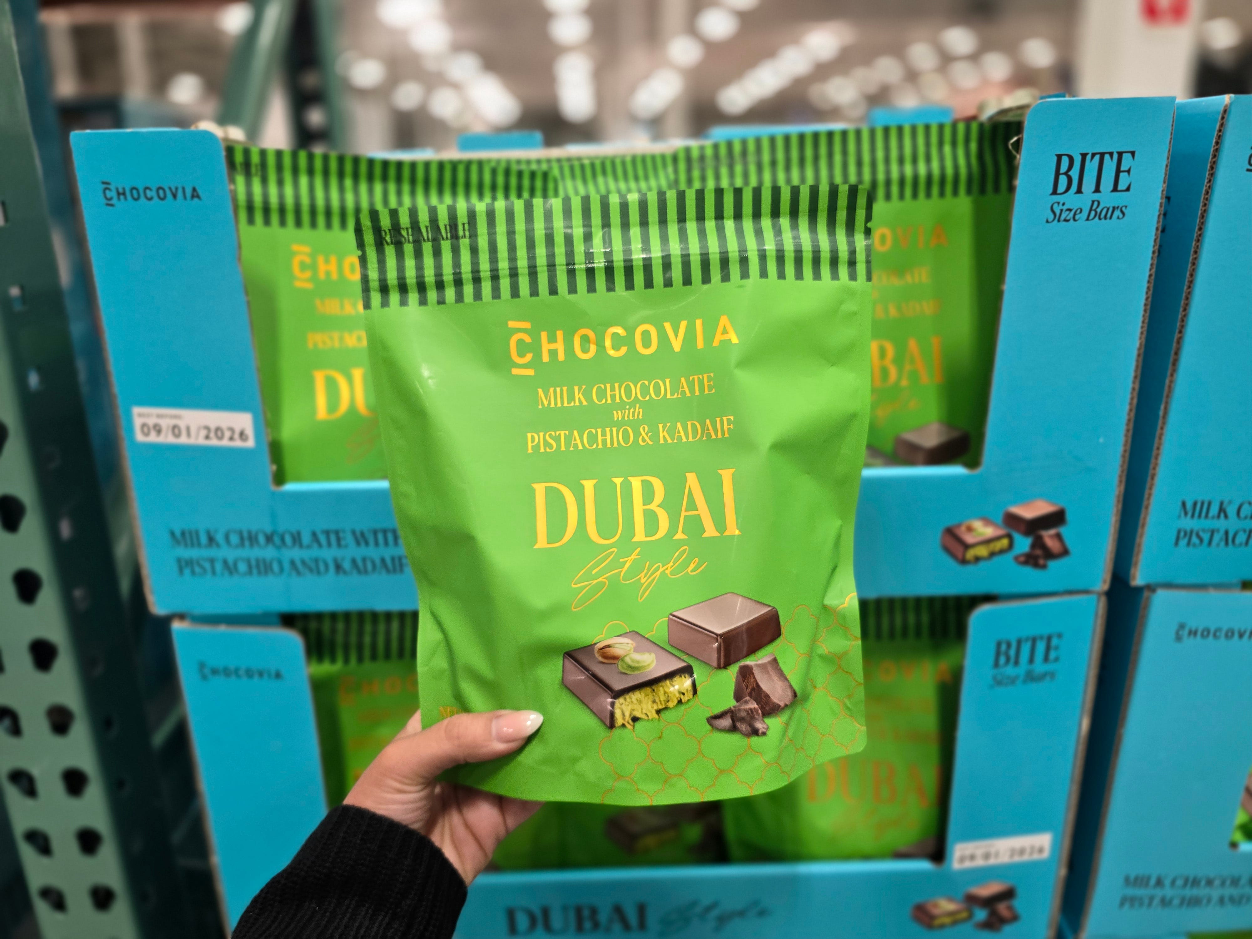 A woman's hand holding a green bag of Chocovia Dubai-style chocolates.