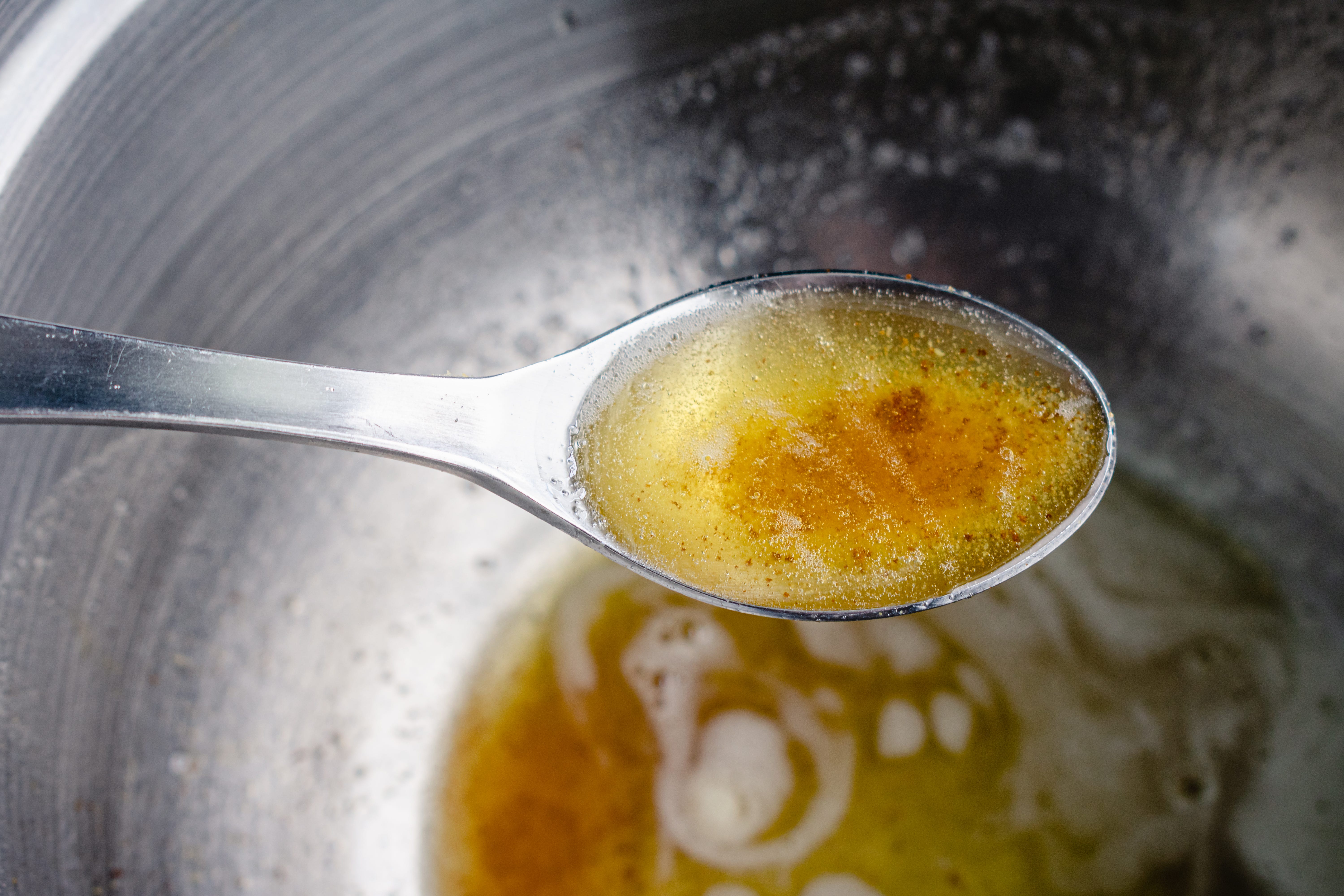 Browned butter in spoon held over mixing bowl