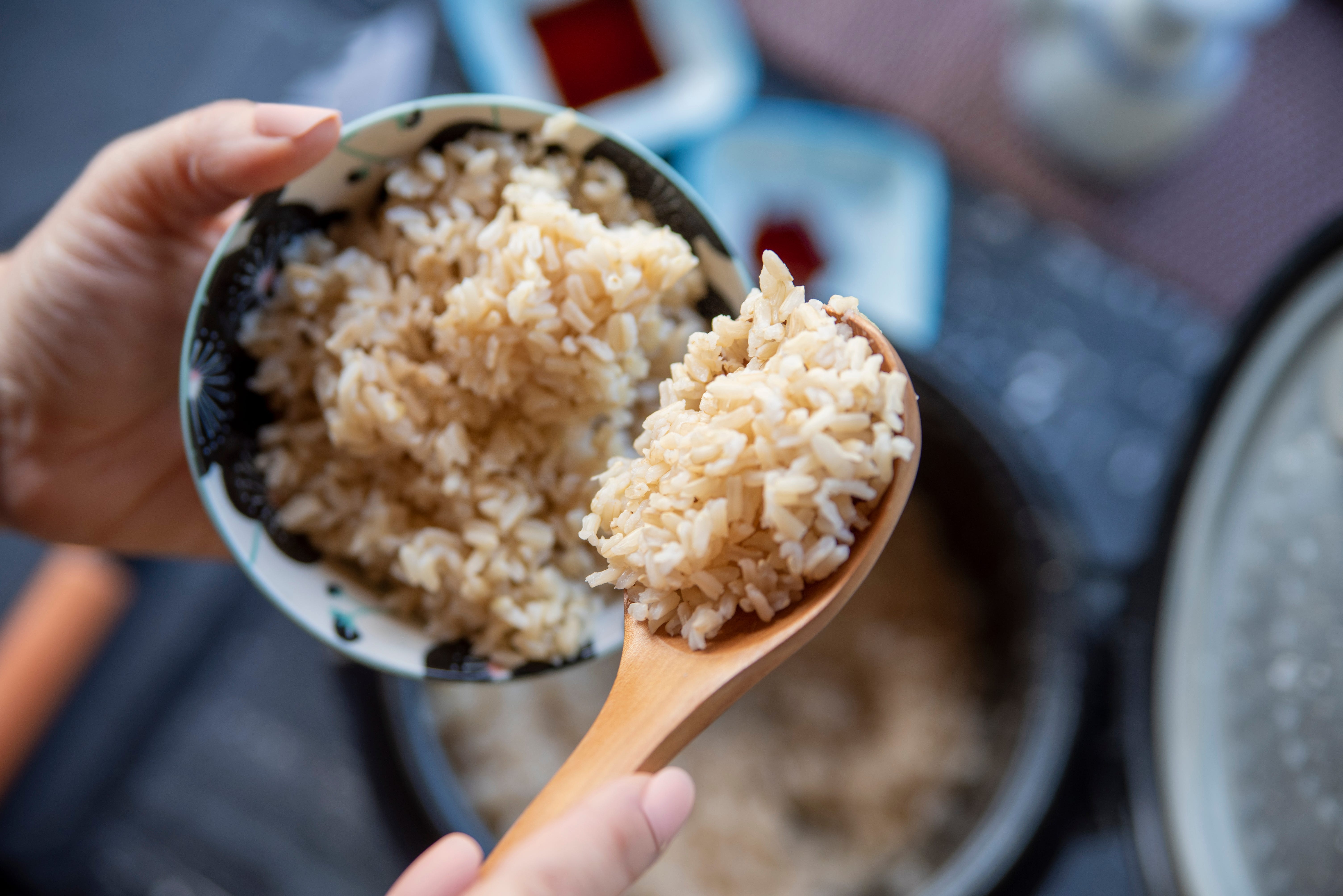 Rice in spoon being placed in bowl someone is holding