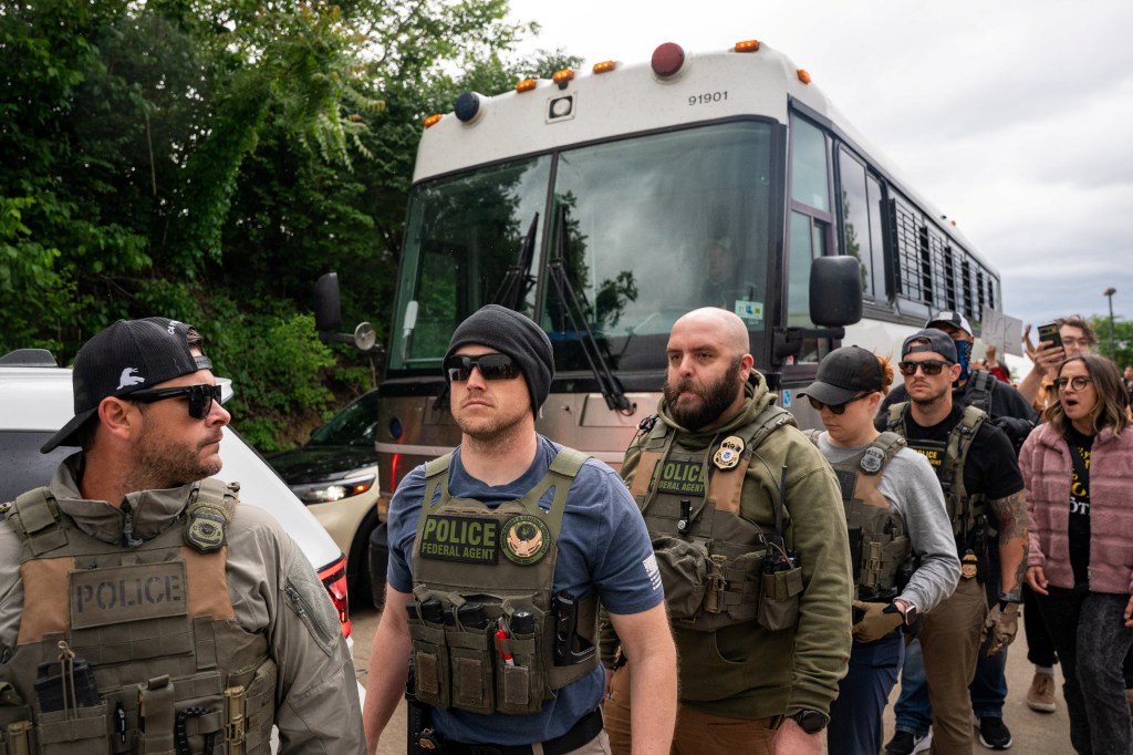 Immigration and Customs Enforcement agents walk in front of a bus at the Department of Homeland Security's field office in Nashville after protesters gathered on May 4, 2025.