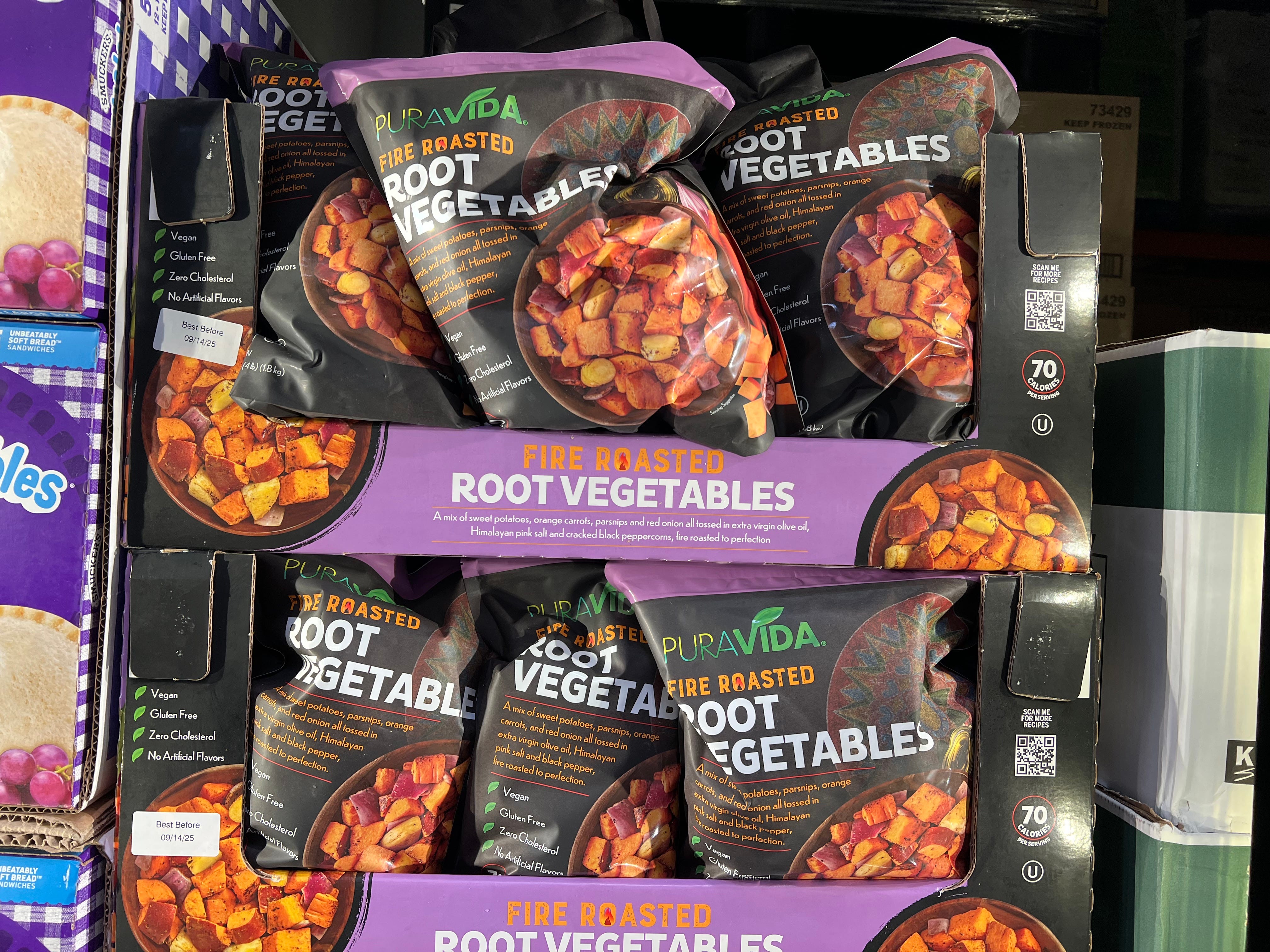 Bags of Pura Vida fire-roasted root vegetables in black boxes on a shelf at Costco.