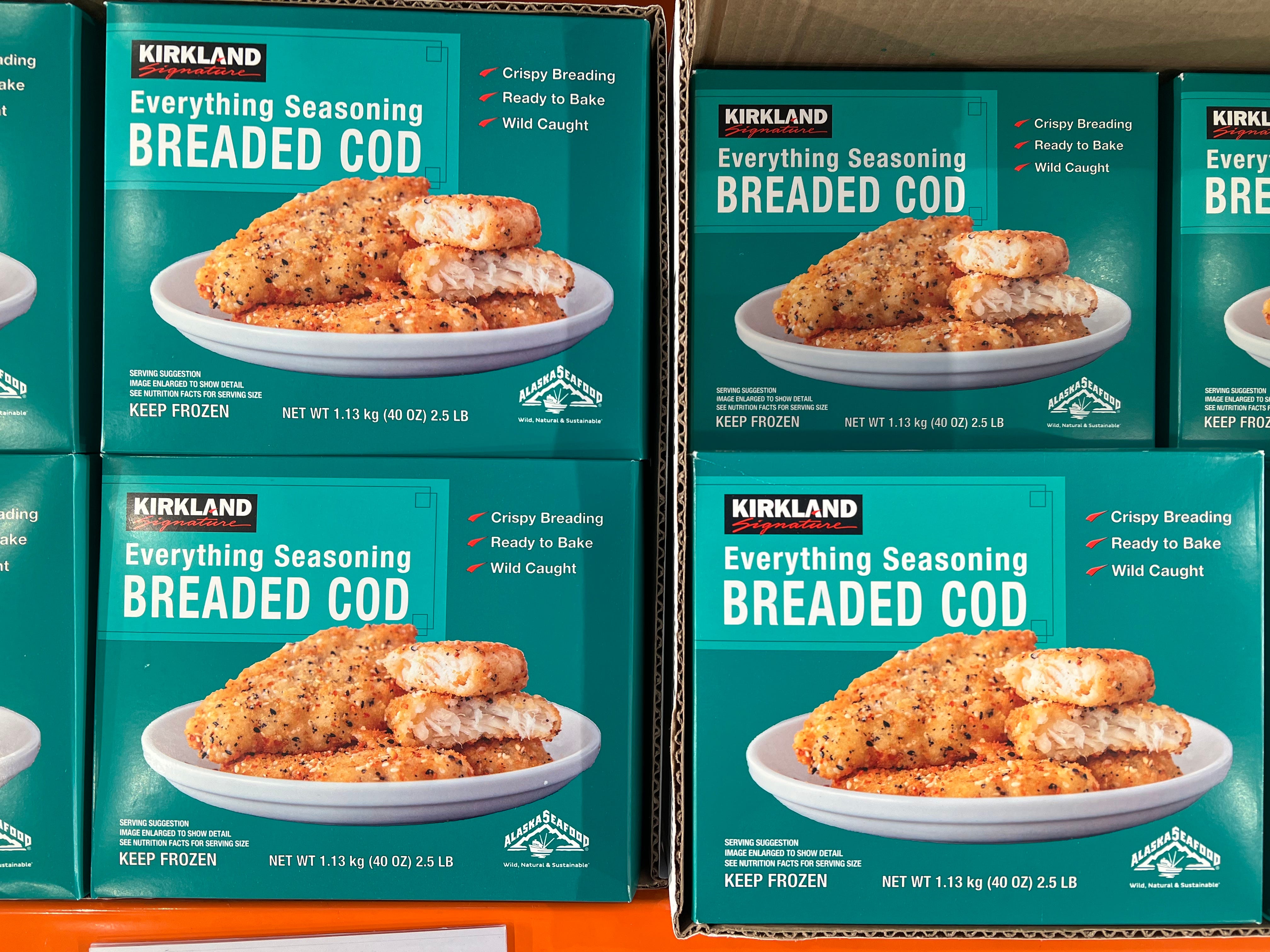 Blue boxes of Kirkland Signature's everything-seasoning breaded cod on shelves in Costco.