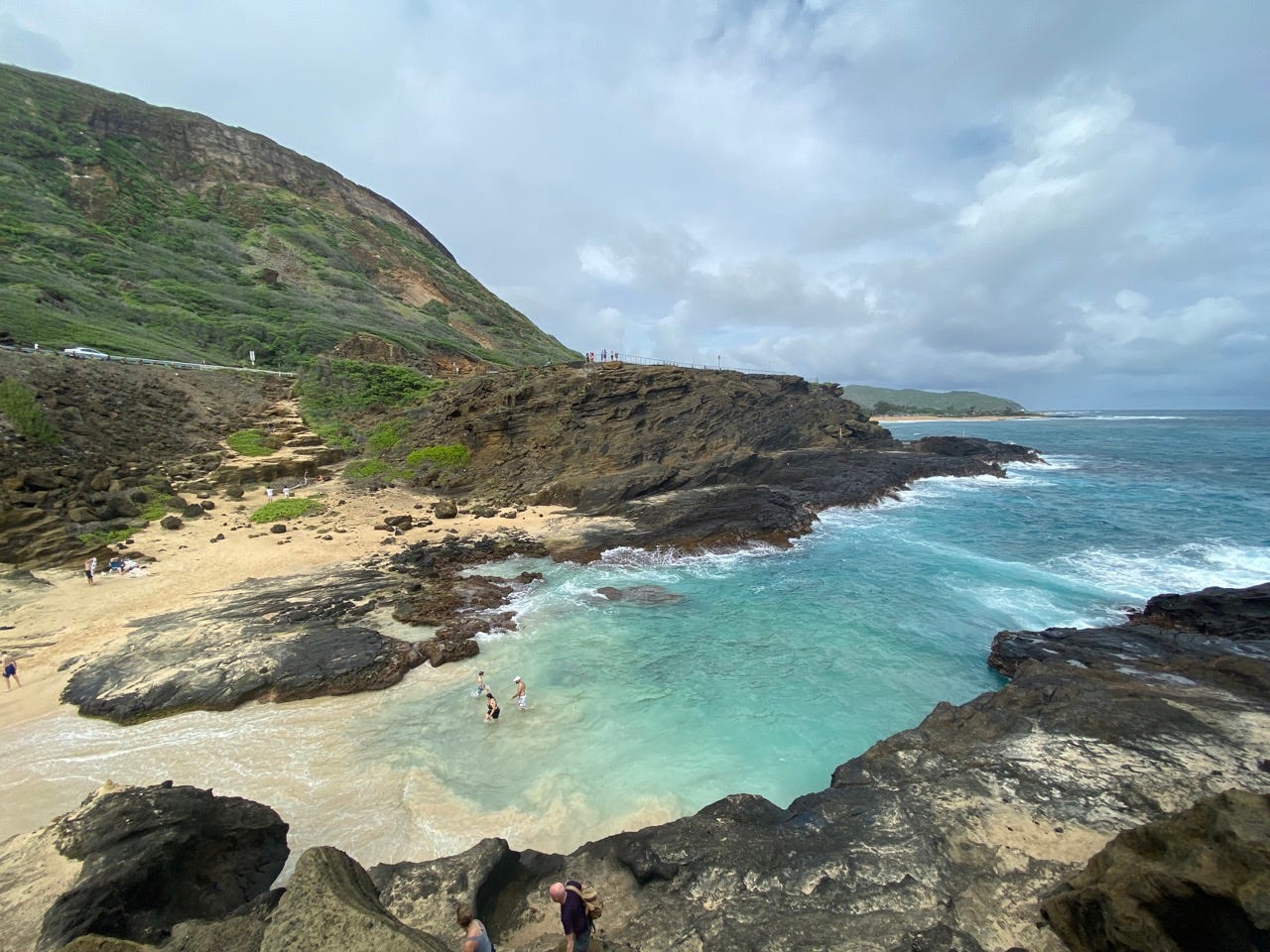 View of rocky cliffs, sand, and clear blue water in Hawaii