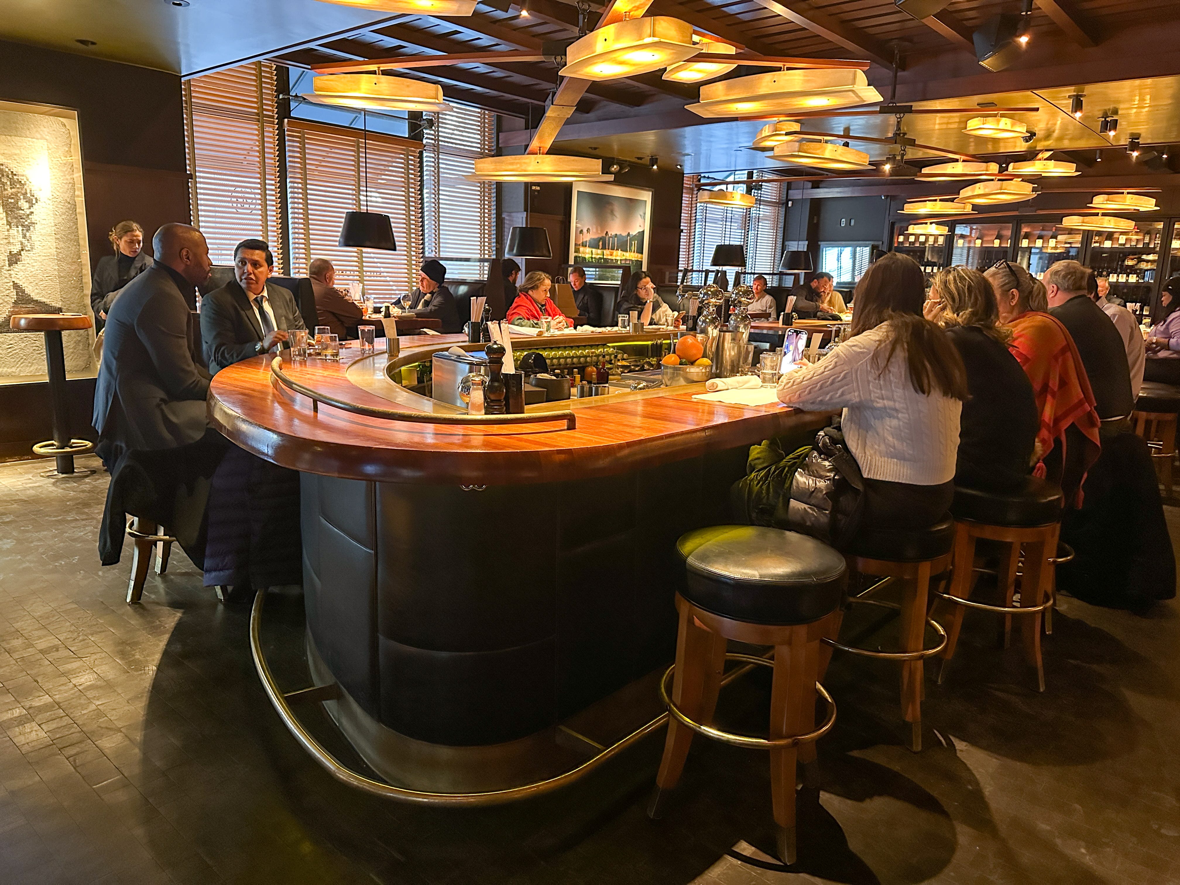 People sitting at a busy bar in a restaurant.