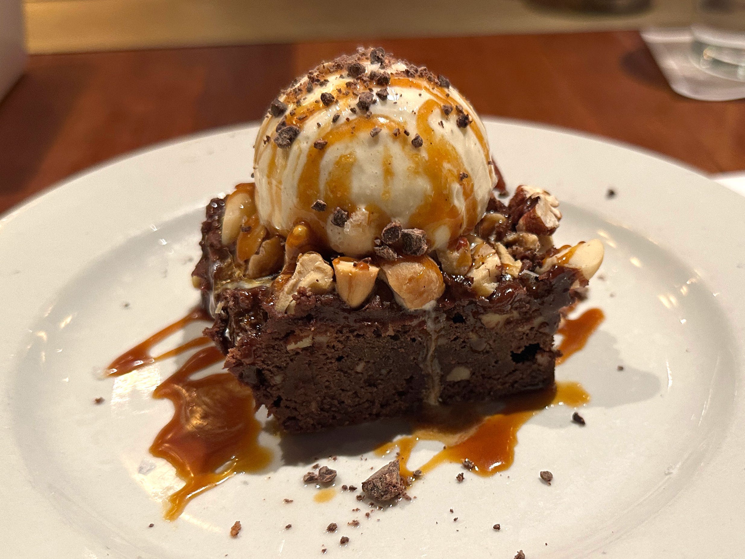 A brownie topped with vanilla ice cream, caramel sauce, and walnuts.