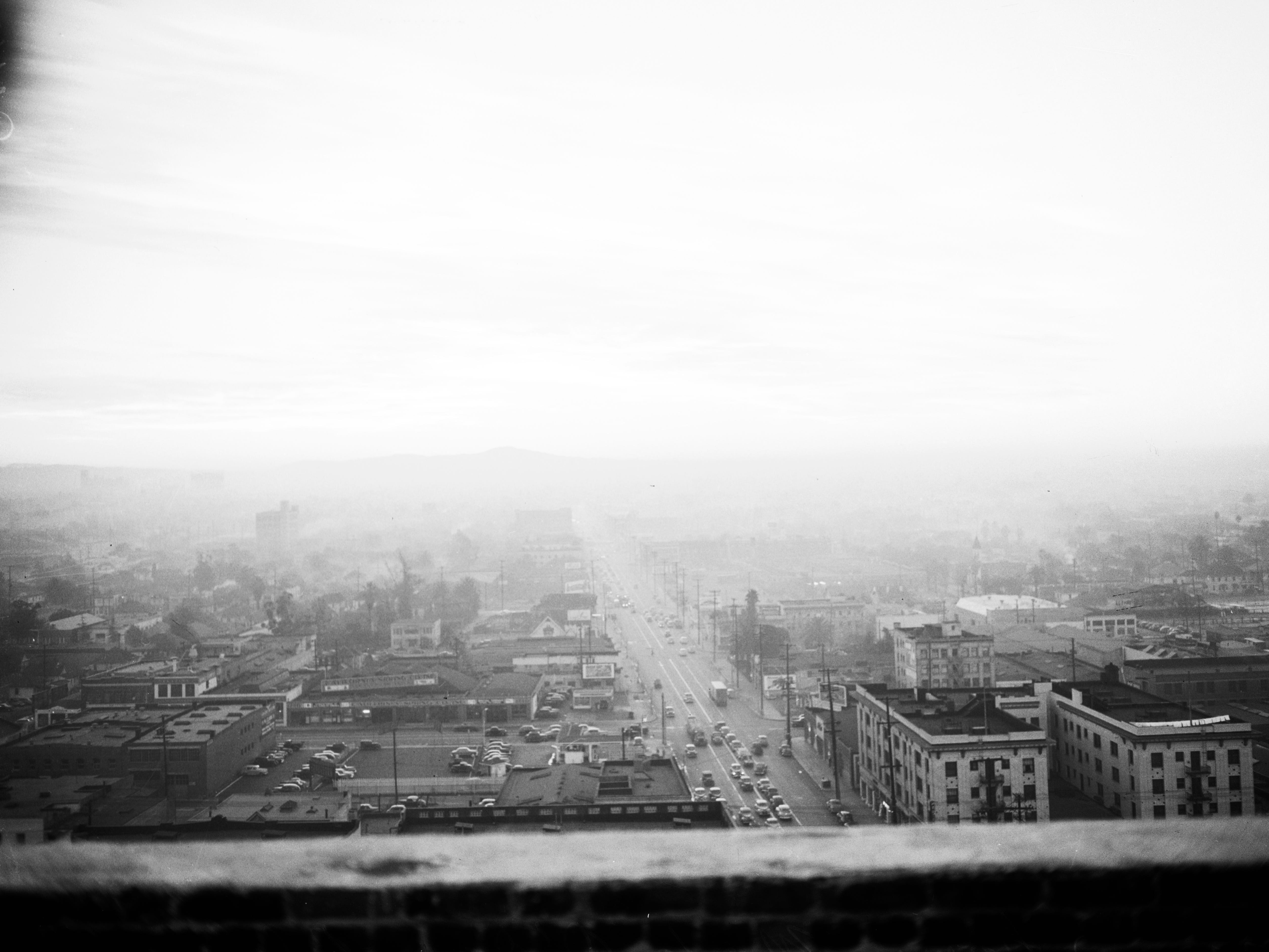 Smog, 9 December 1948. George Ichien (Air Pollution Control Inspector, atop Cecil Hotel looking for violators);Views from various directions from Cecil Hotel;View looking east from Mode-O-Day building at 8 a.m.;Incinerator on Broadway between 15th & 16th Streets smoking. (Sleeve reads: 9593 was 8042).South Broadway (between 15th & 16th Streets); Los Angeles, California.