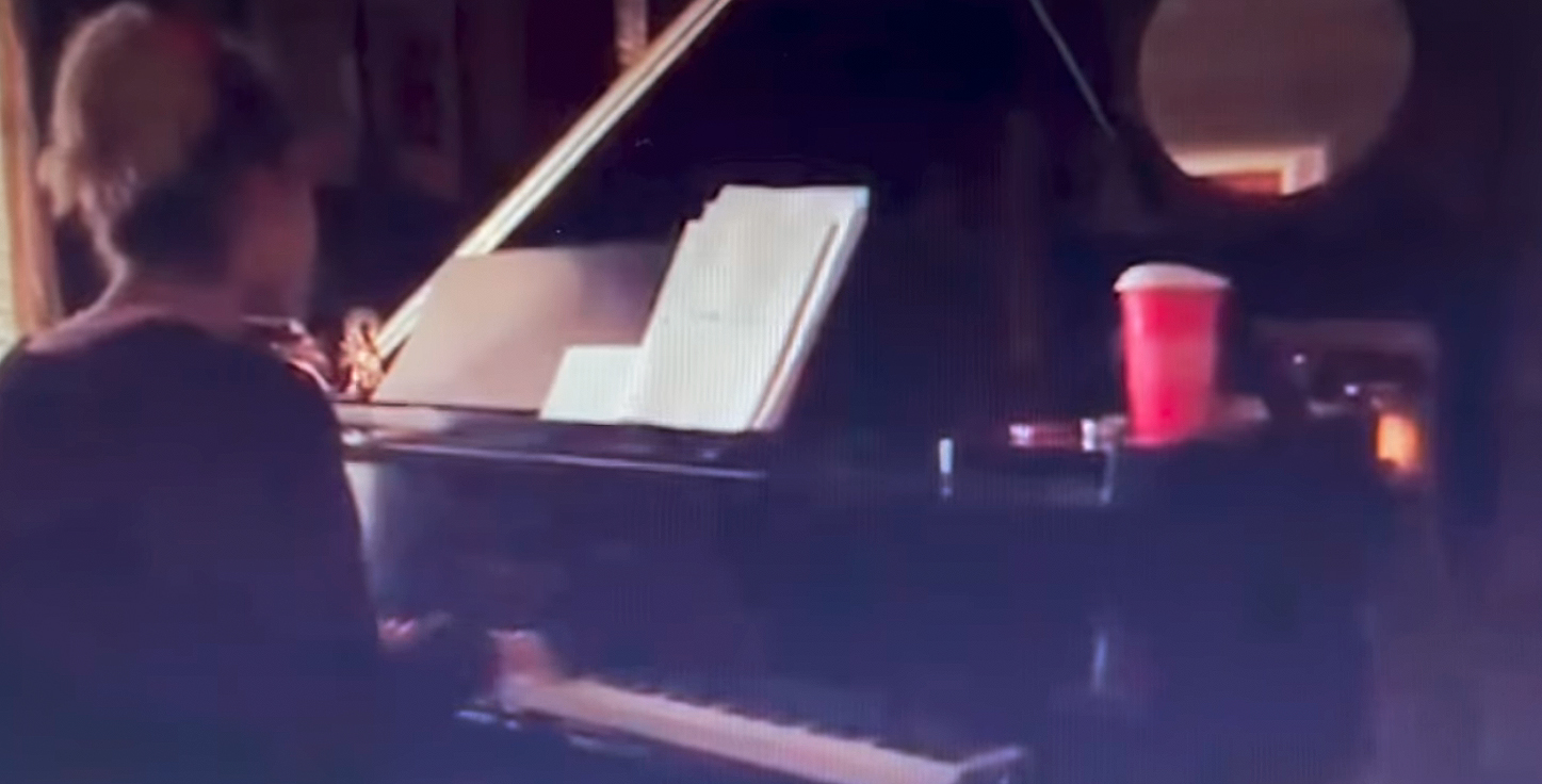 A screenshot of a video of Miley Cyrus playing the piano. 