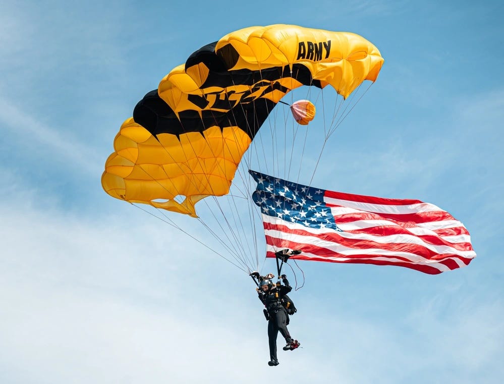 A member of the US Army Golden Knights Parachute Team descends with a large American flag.