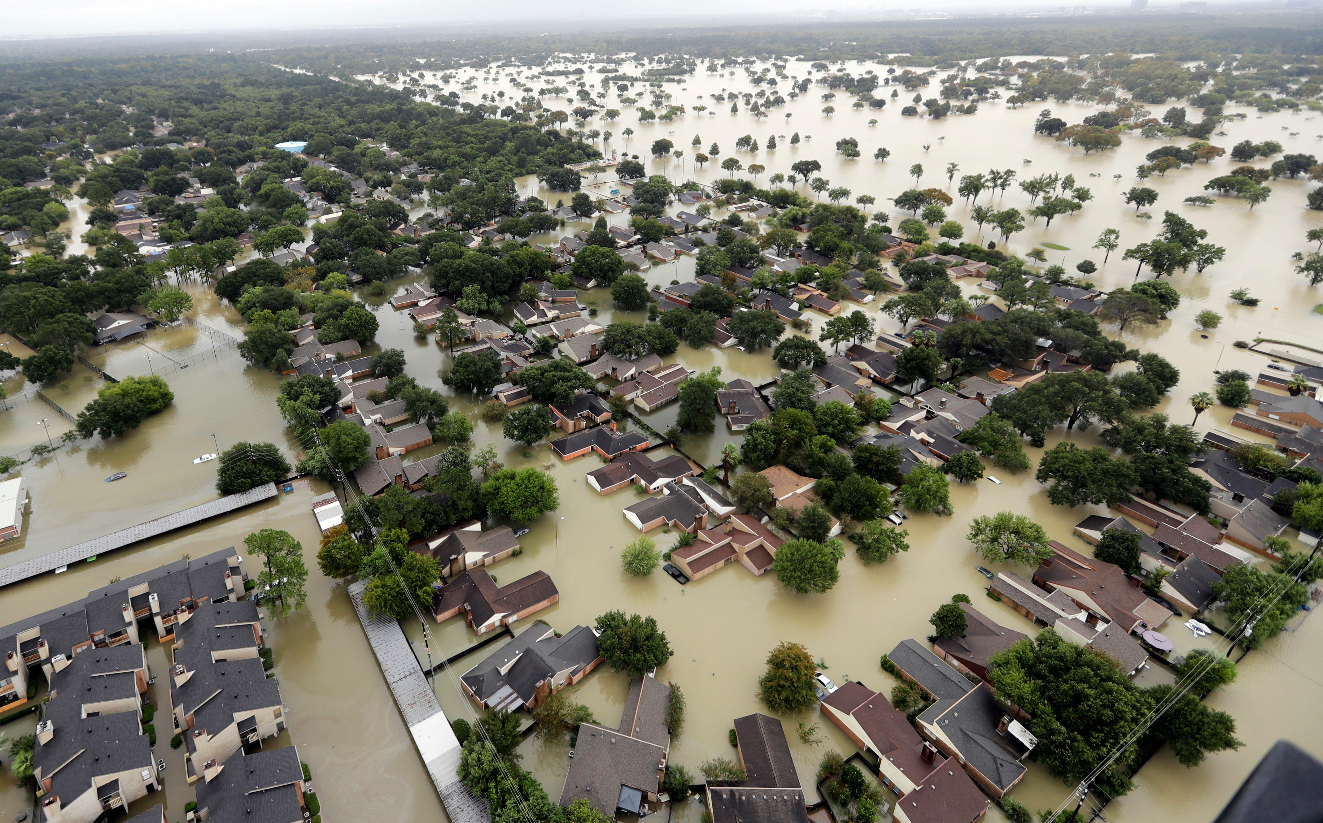 FILE - In this Aug. 29, 2017, file photo, water from Addicks Reservoir flows into neighborhoods from floodwaters brought on by Tropical Storm Harvey in Houston. A trial has begun to determine if residents can be compensated after their homes and businesses were flooded by two reservoirs during Hurricane Harvey in 2017. The two-week trial in Houston federal court, which started Monday, is focusing on 13 flooded properties serving as test cases to determine whether the federal government would be liable for damages. Lawyers representing the federal government say flooding from a storm of Harvey's size was