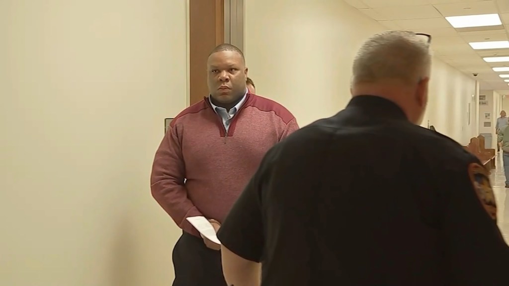 Kevin Ware Jr. is escorted through the halls of a court house while handcuffed.