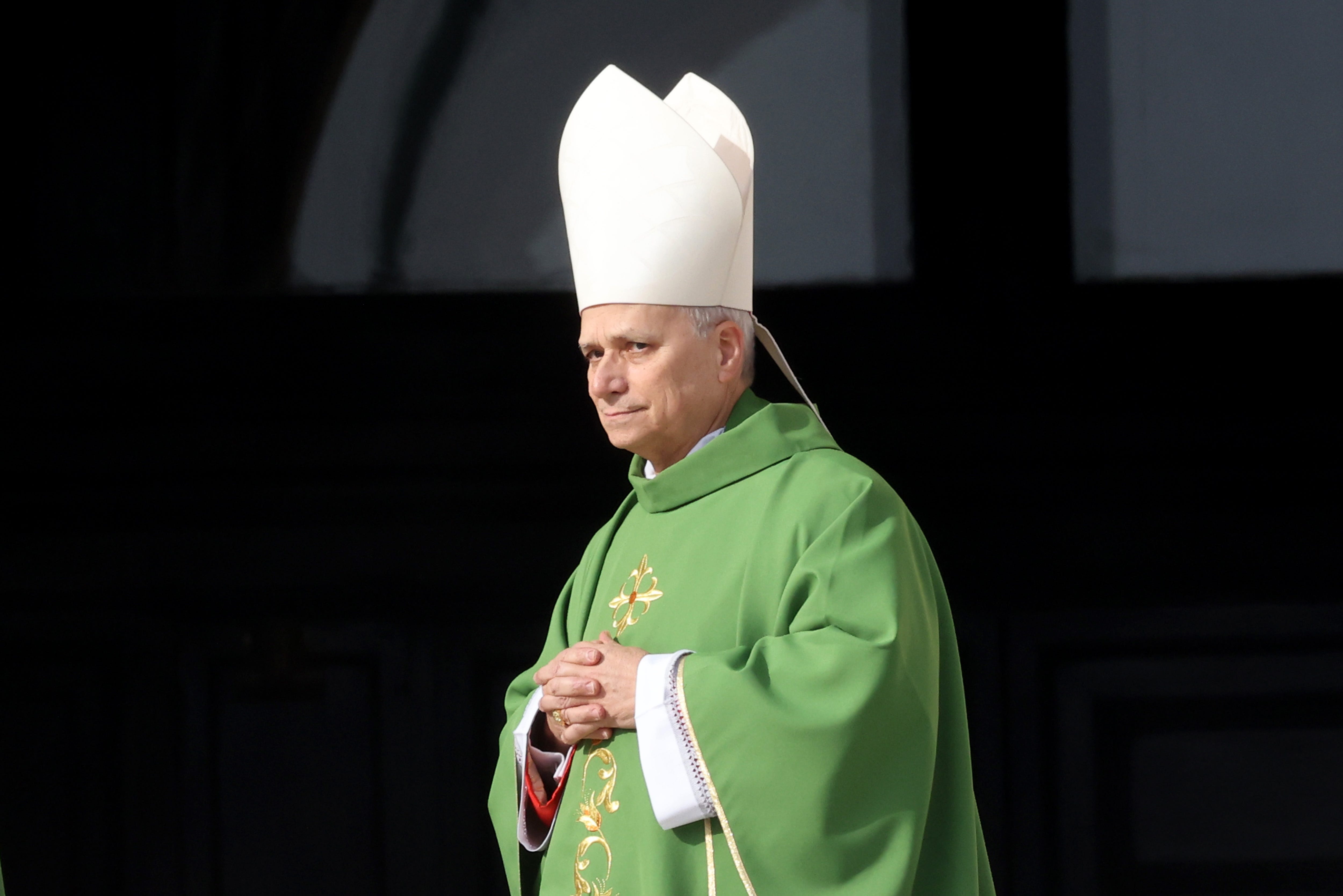 Pope Leo XIV in green and tall white hat holding his hands together