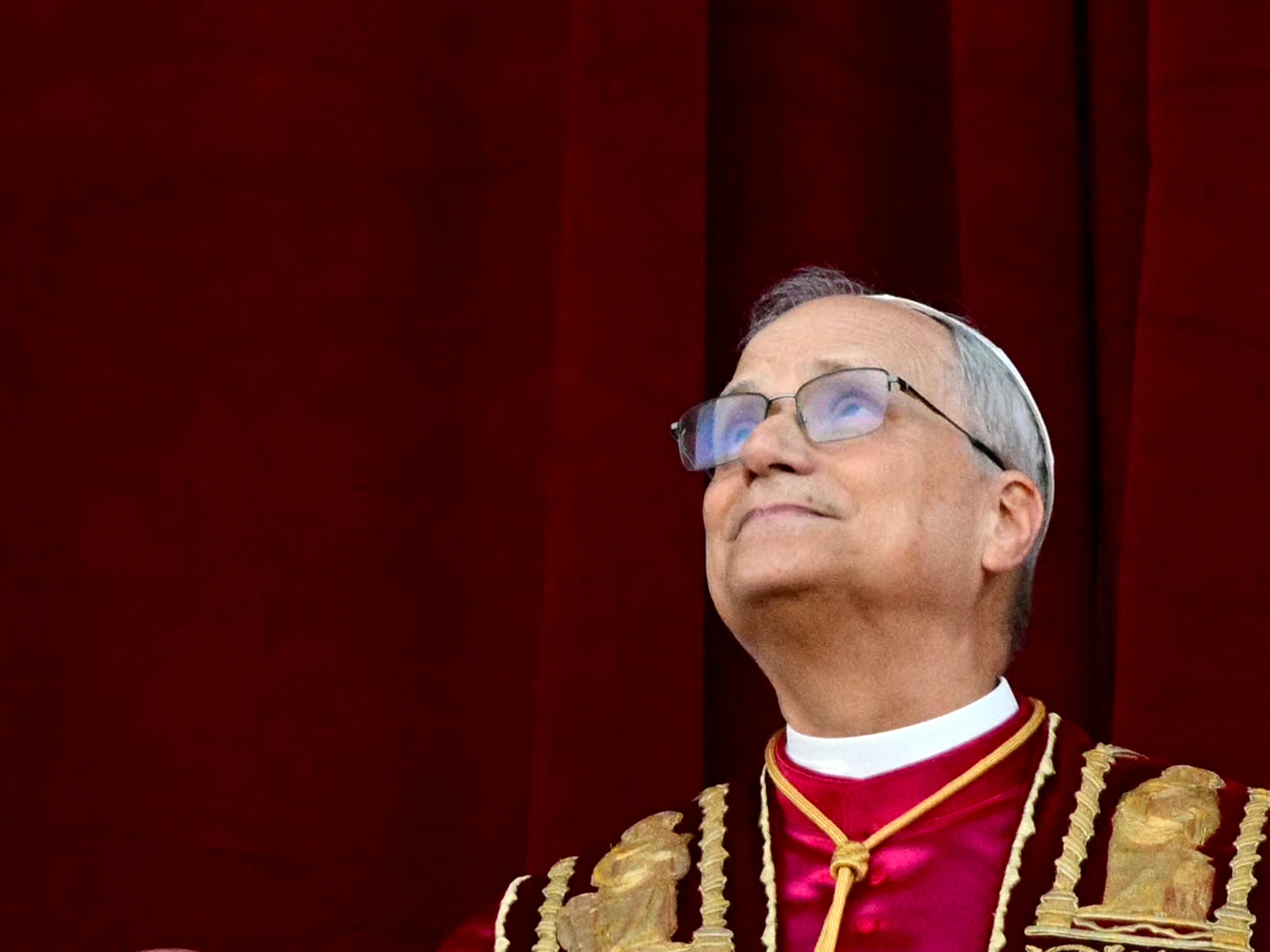 Pope Leo XIV stands in front of a red curtain