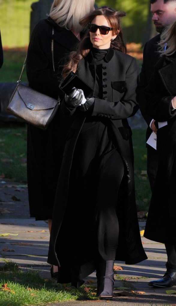 Cheryl Cole in a sunglasses and black coat, and black pants.