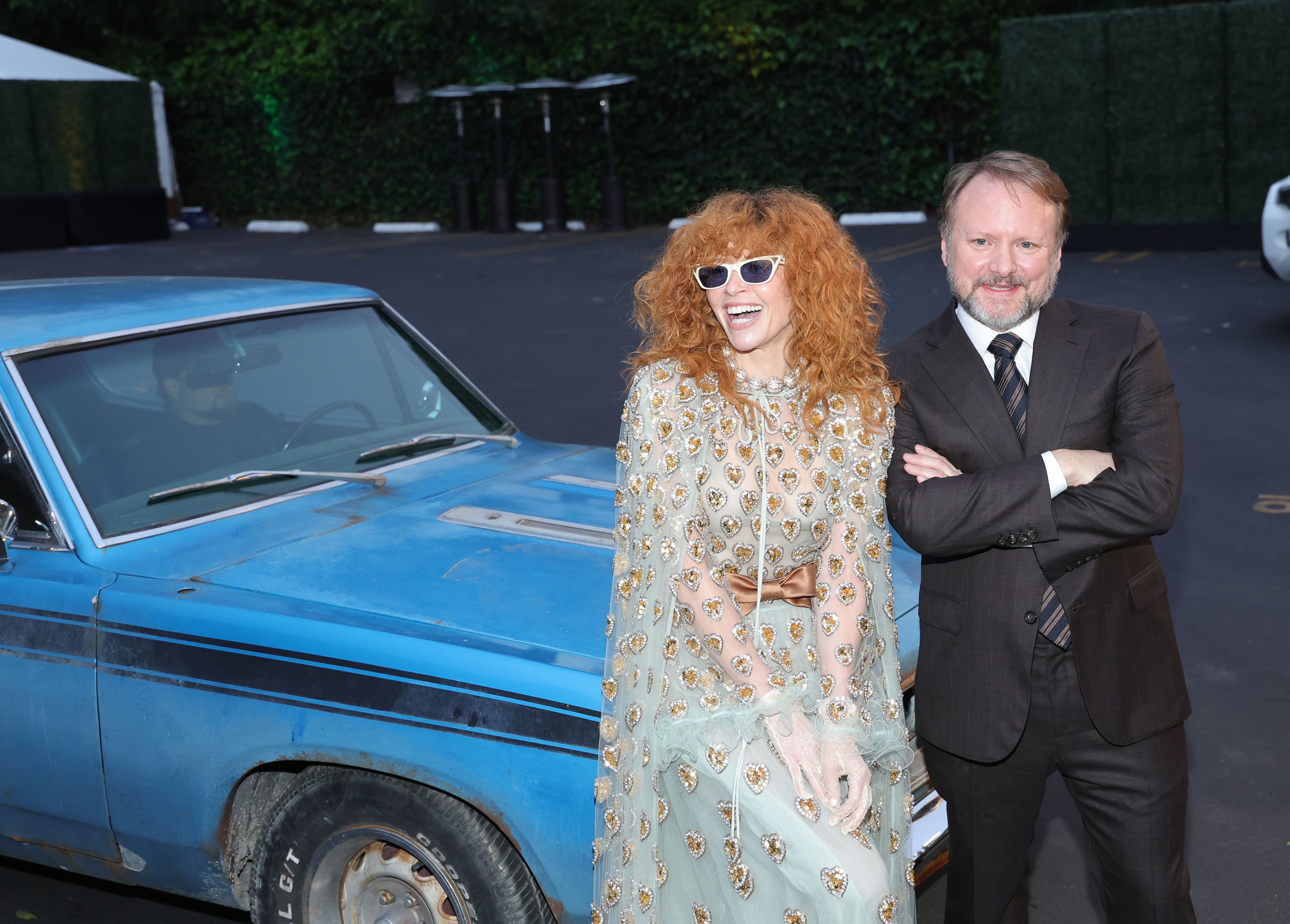 Natasha Lyonne and Rian Johnson leaning against a car