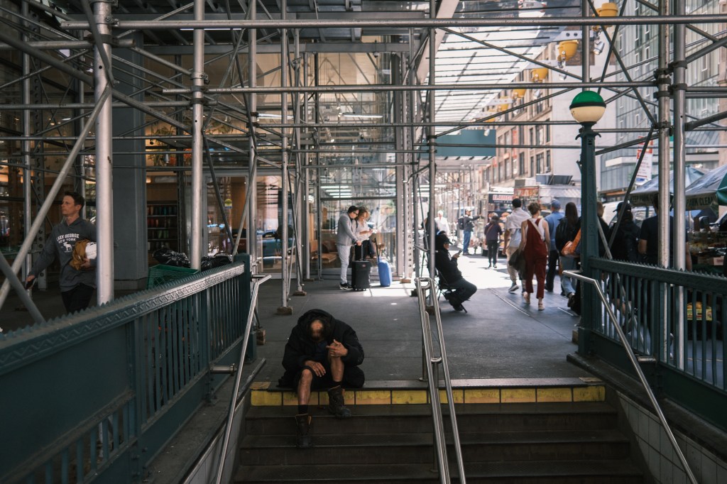 A homeless person sits on the steps of the Times Square subway station in midtown Manhattan