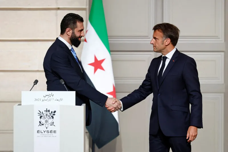 French President Emmanuel Macron (right) shakes hands with Syrian President Ahmed al-Sharaa after a joint press conference following a meeting at the Élysée Palace in Paris on May 7.