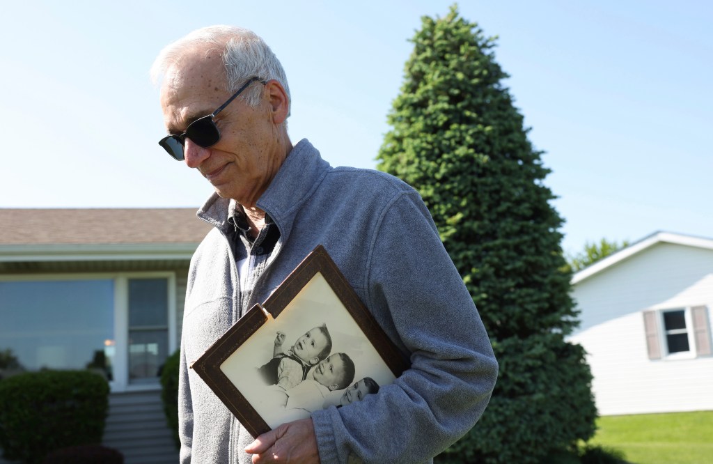 John Prevost holding a 1958 portrait of the three Prevost brothers, including new Pope Leo XIV, while talking to reporters outside his home in 2025