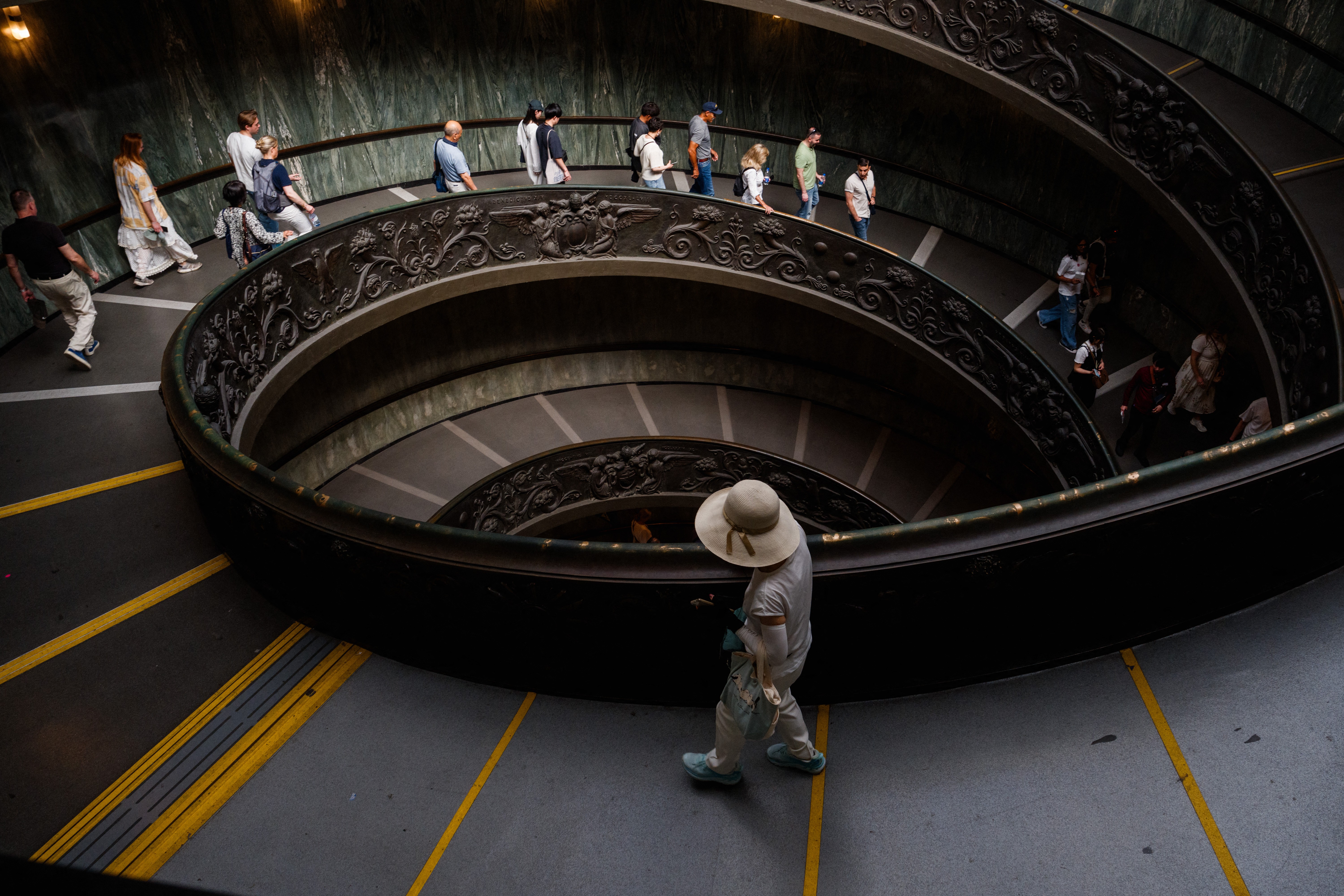 People descend down a wide spiral staircase.