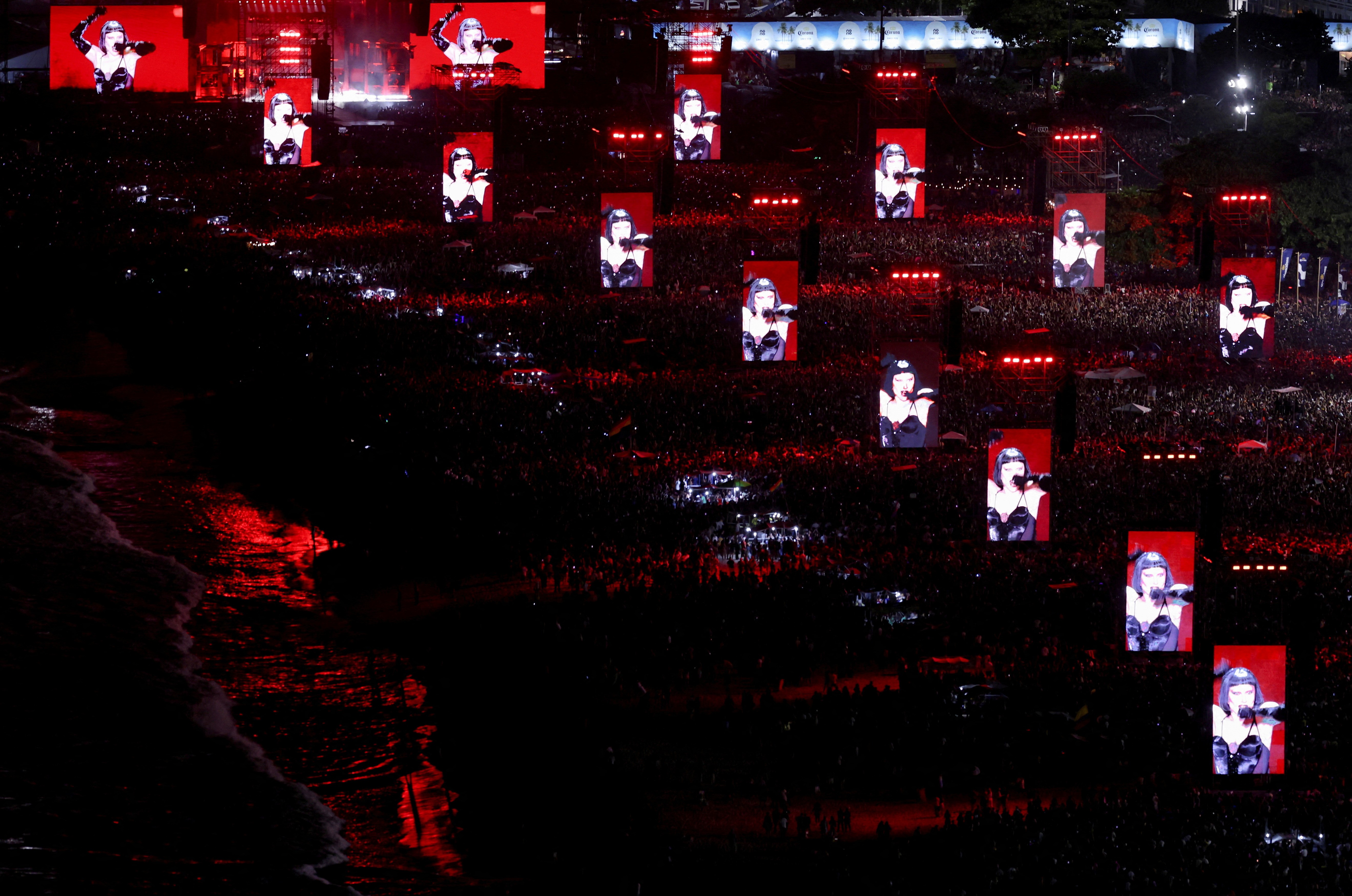 More than a dozen large video screens stand across a broad beach in Rio de Janeiro, showing Lady Gaga in performance.