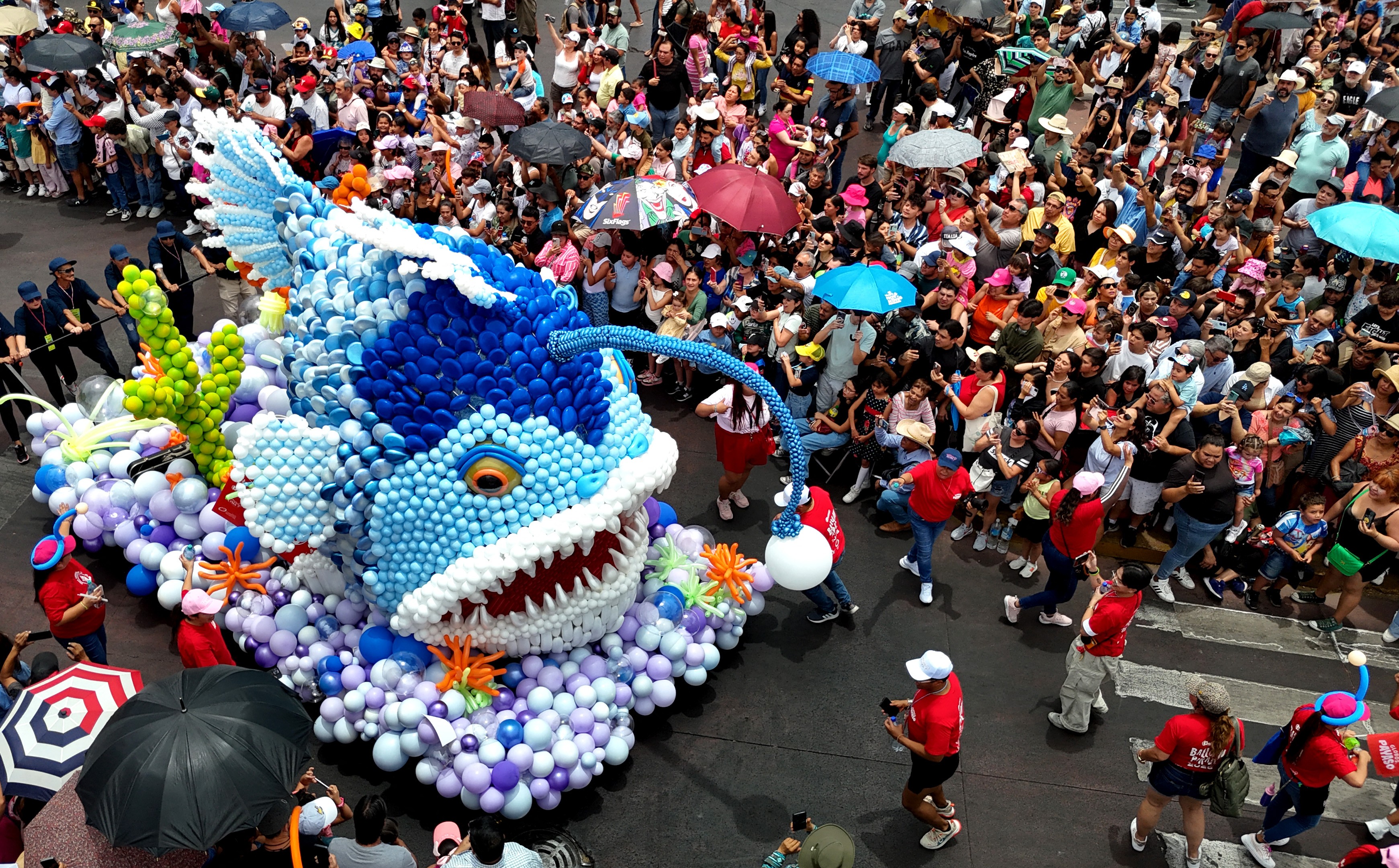 An elevated view of a parade, featuring a float depicting an anglerfish made out of balloons