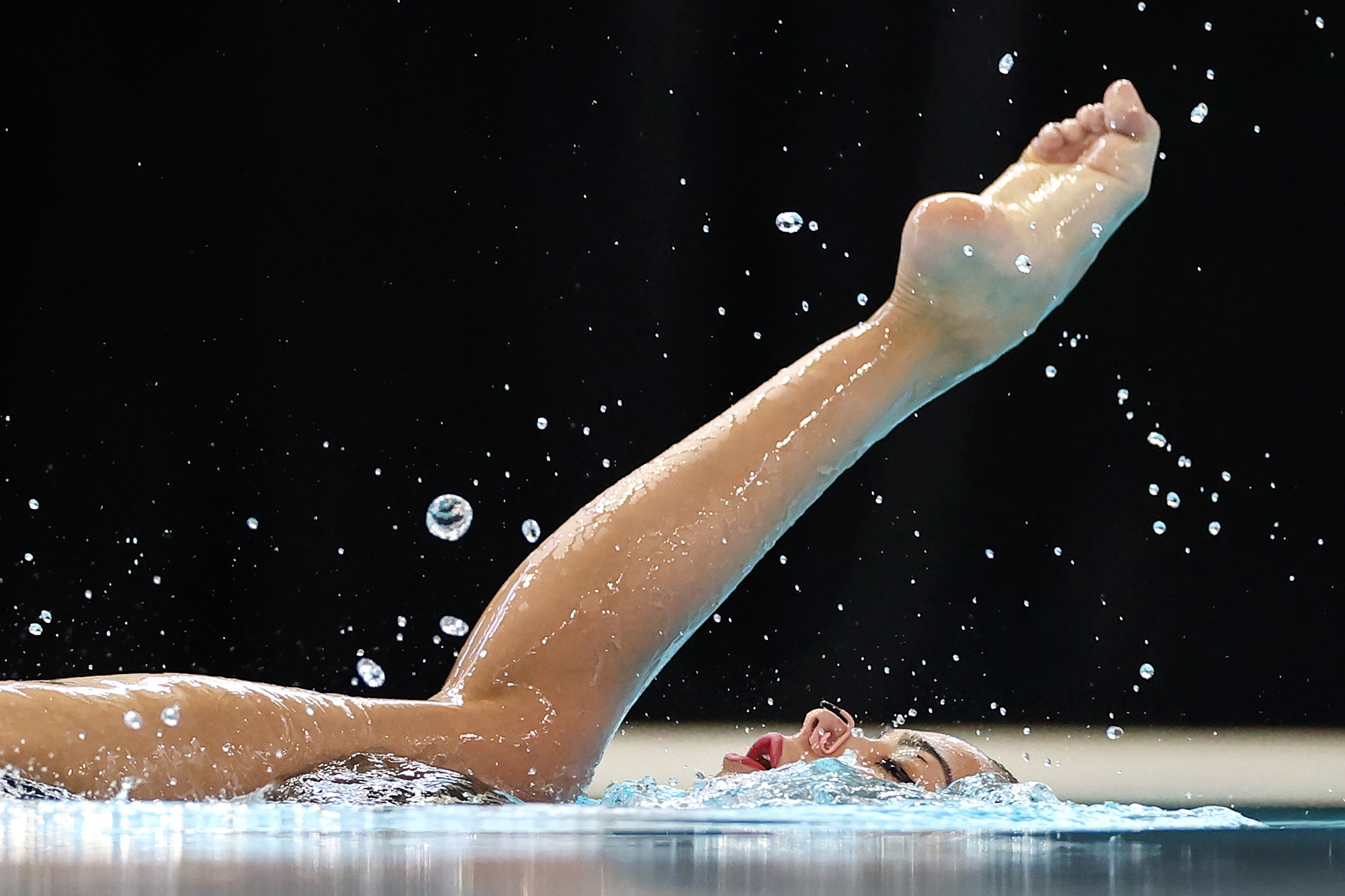 A swimmer lifts a leg out of the water during a competition.
