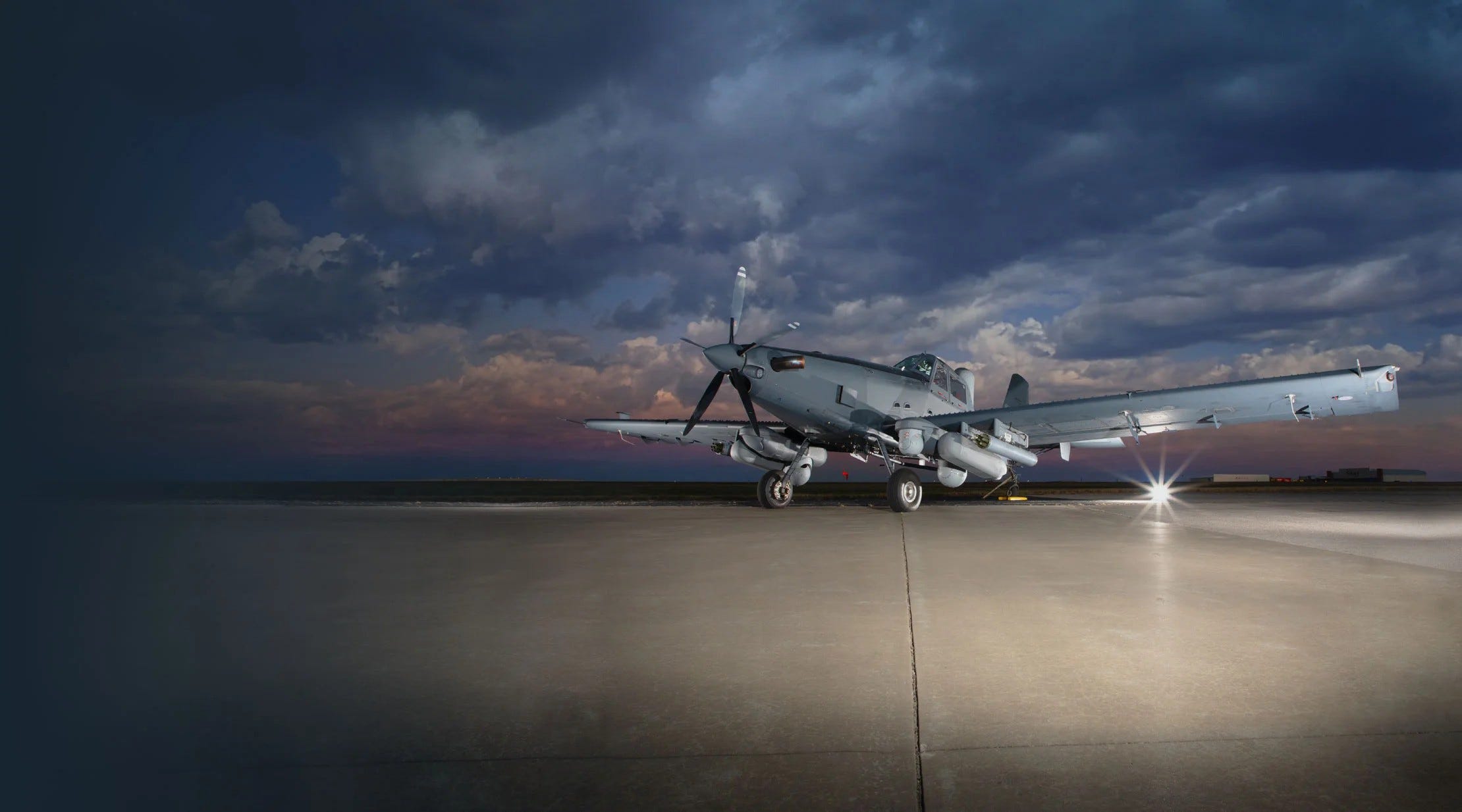 L3Harris' Sky Warden airplane is seen sitting on concrete with a cloudy sunset in the background.