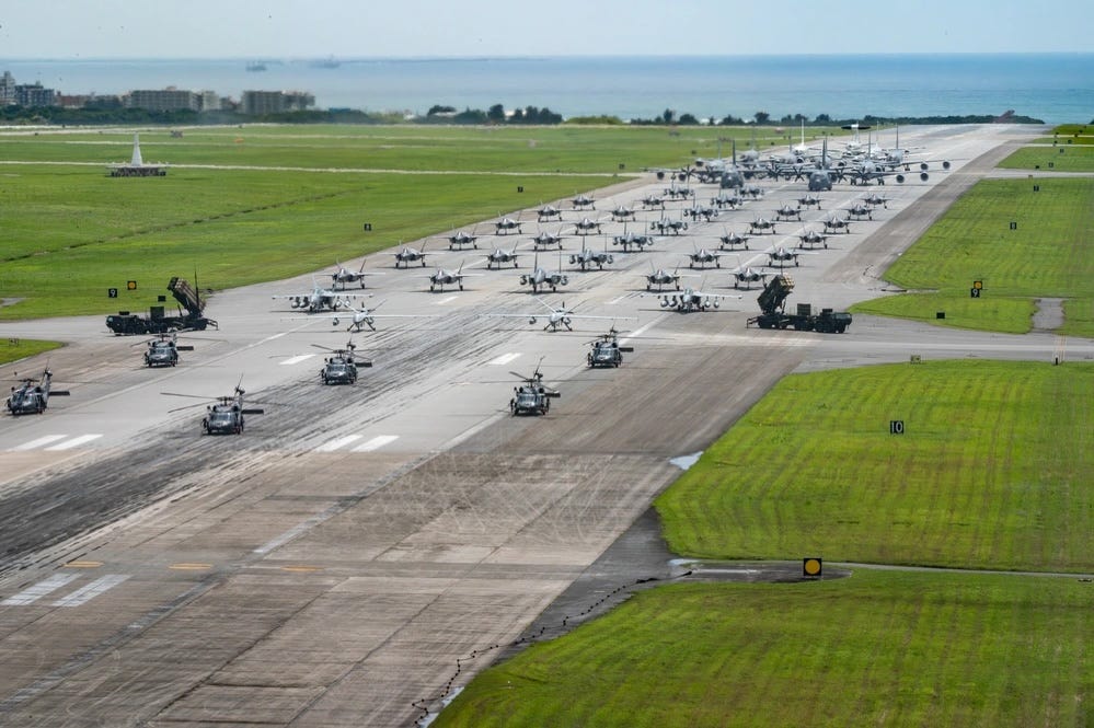 US Air Force, Army, and Navy aircraft and equipment line up on a runway for an elephant walk at Kadena Air Base.