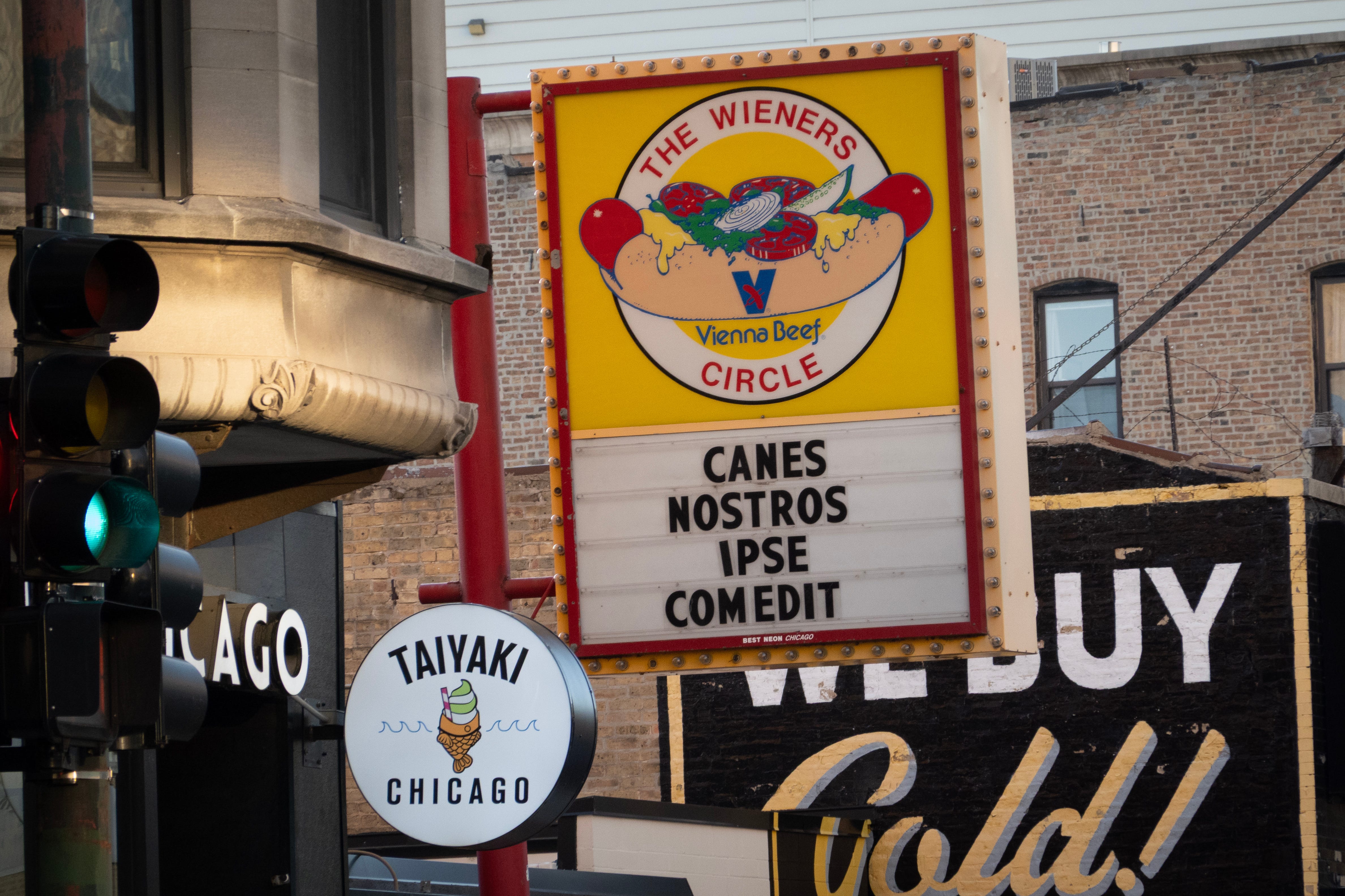 A yellow and red Weiners Circle sign saying "Canes Nostros Ipse Comedit"