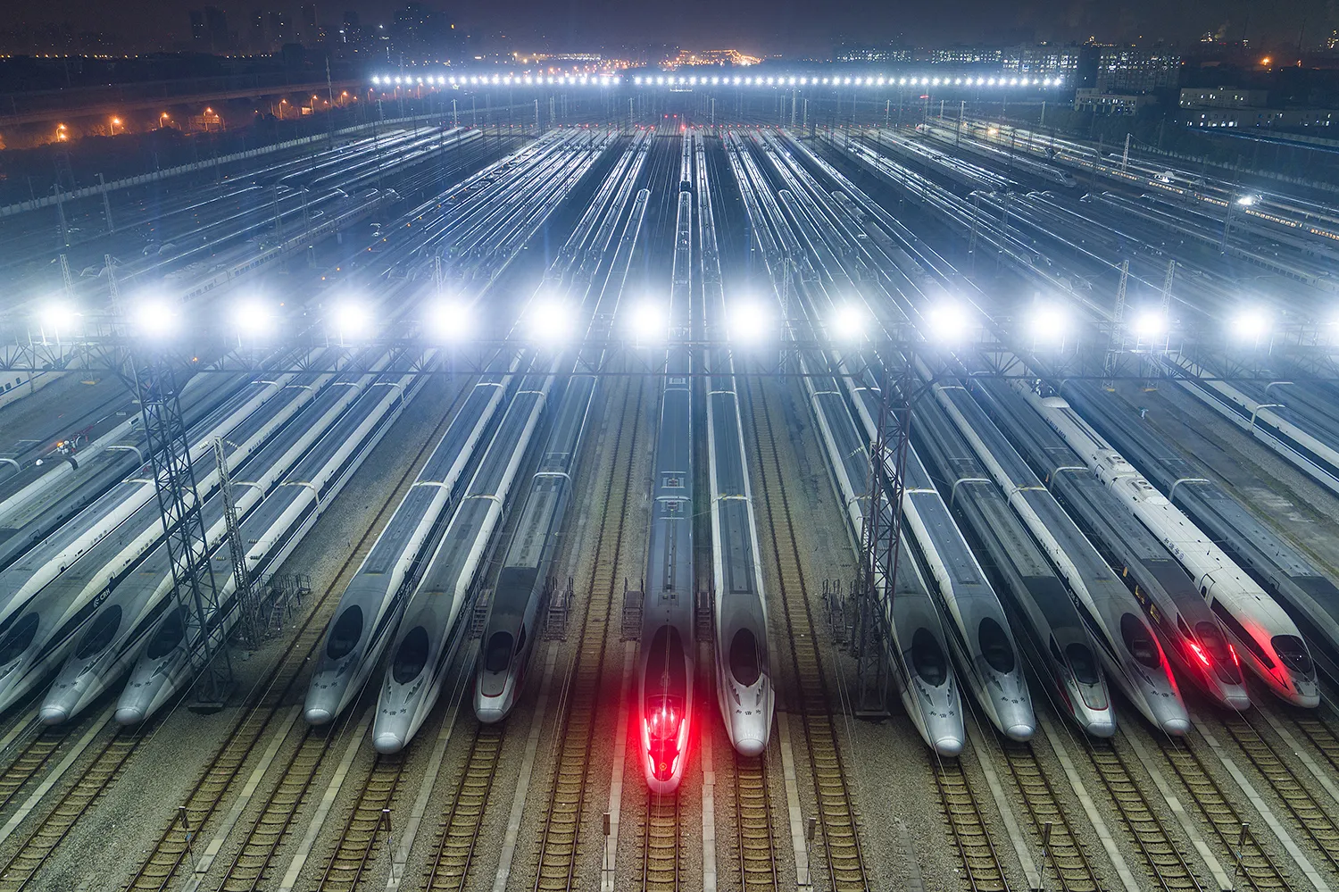 A high-angle view shows tracks with rows of high-speed trains.
