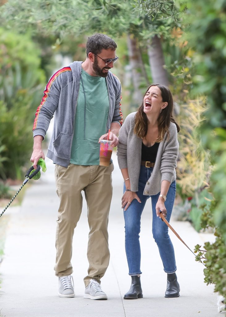 Ben Affleck walking a dog with Ana De Armas who is laughing. 