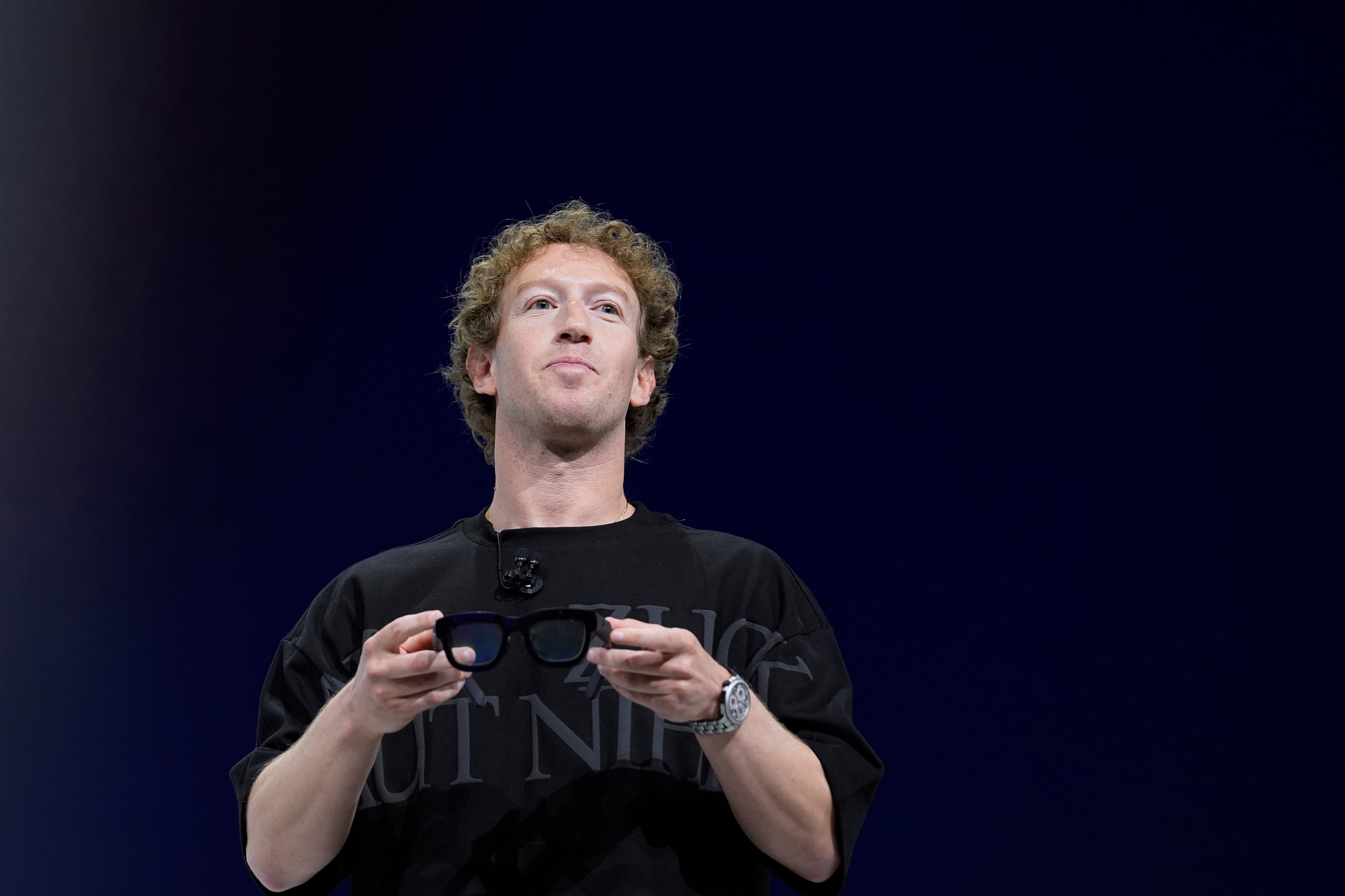 Mark Zuckerberg holds a pair of Orion AR glasses and wears a silver watch.