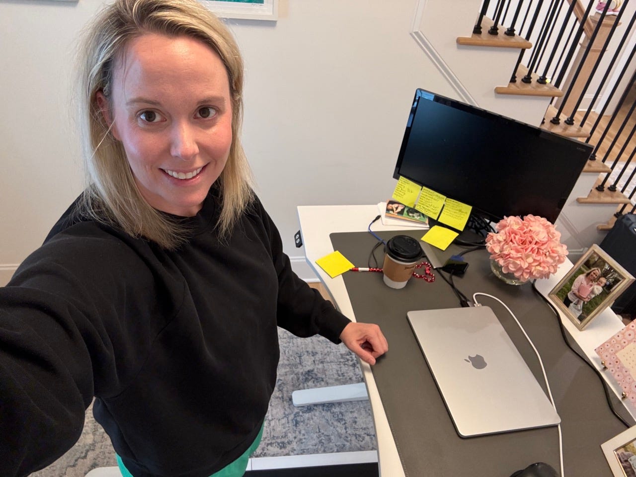 Author Elliott Harrell smiling at her desk, standing on walking pad