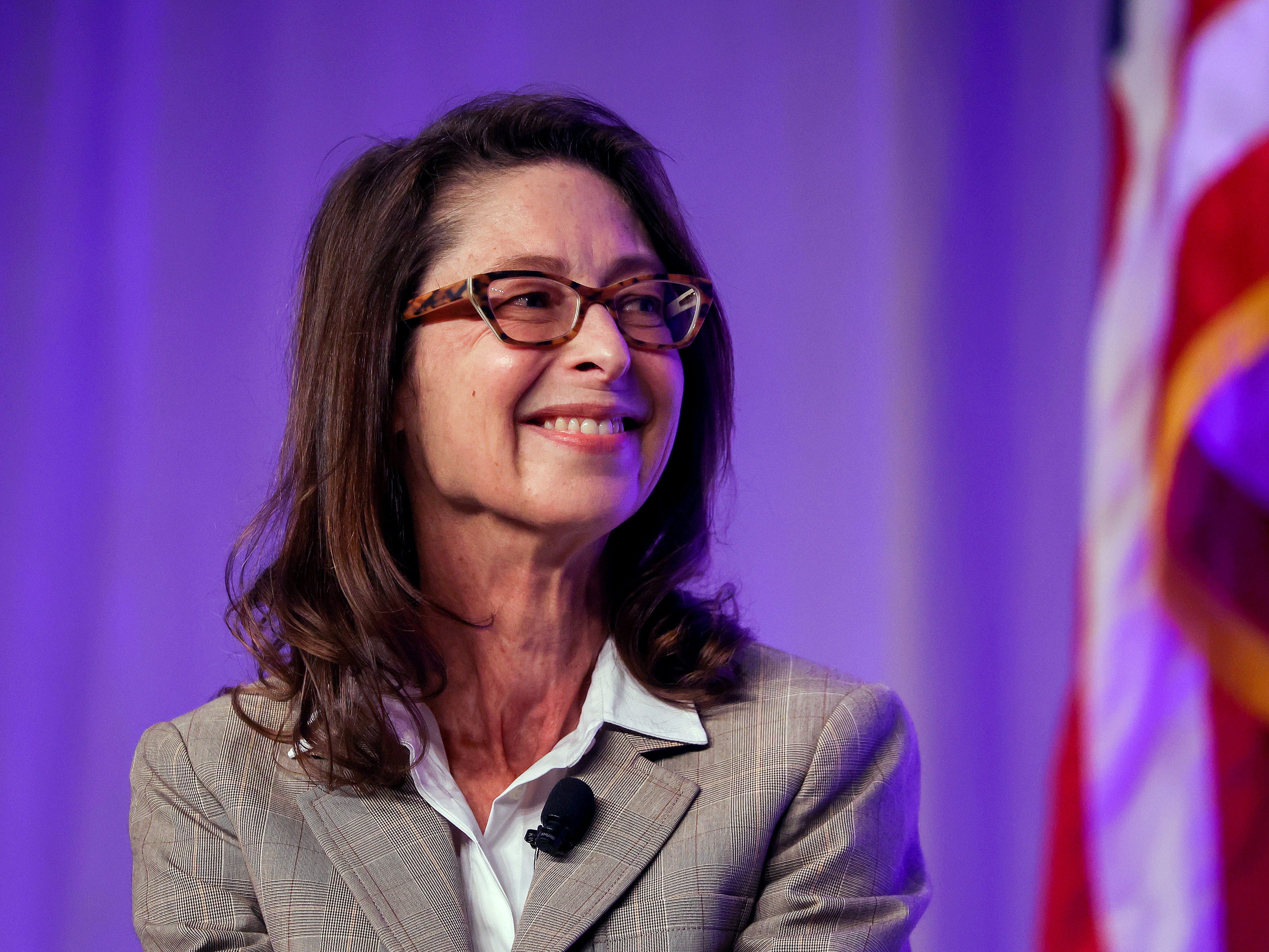 Abigail Johnson smiles in front of a purple backdrop with an American flag behind her