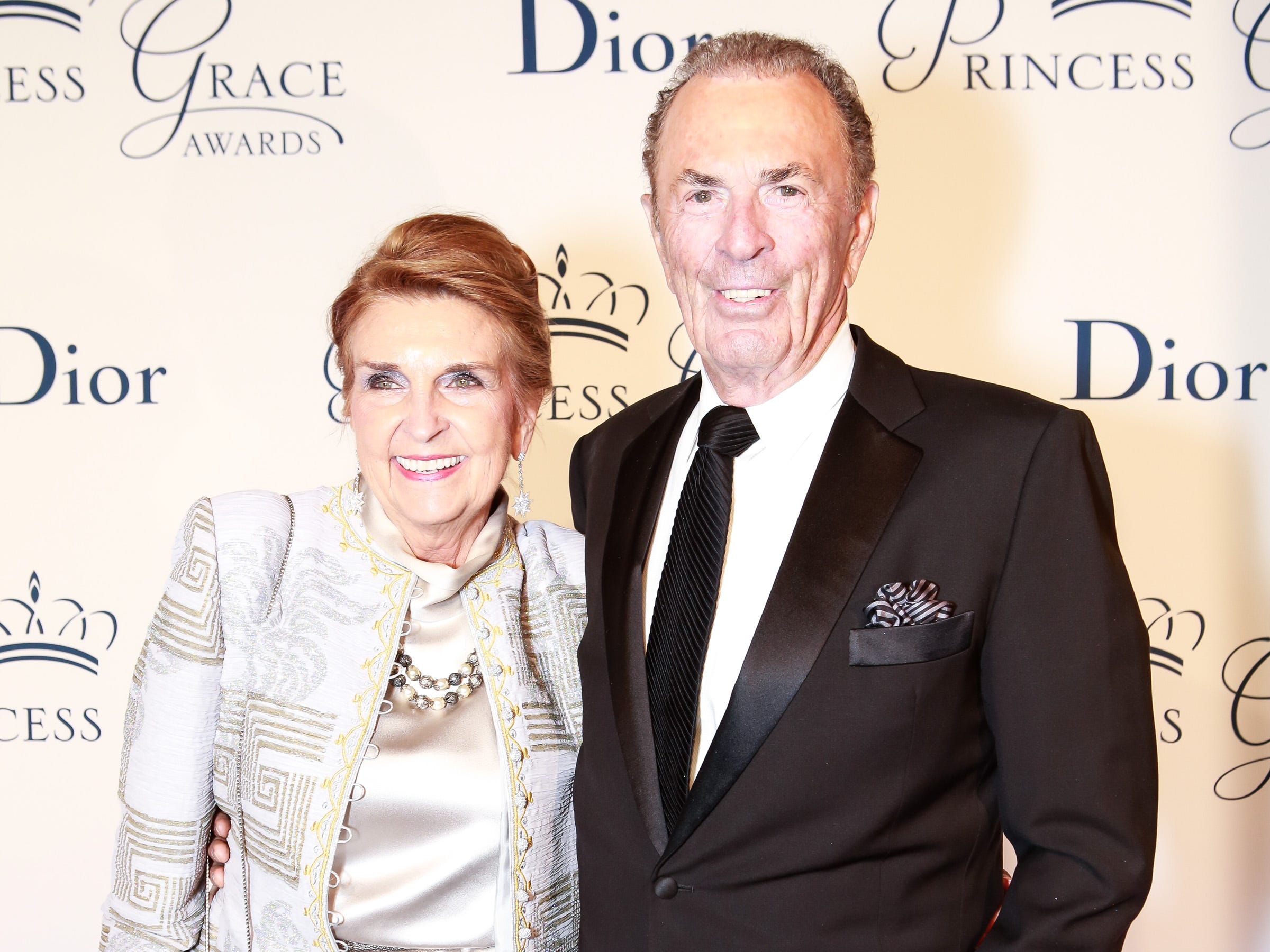 Phyllis Washington and Dennis Washington in formal attire stand in front of a beige backdrop that reads Dior and Princess Grace Awards