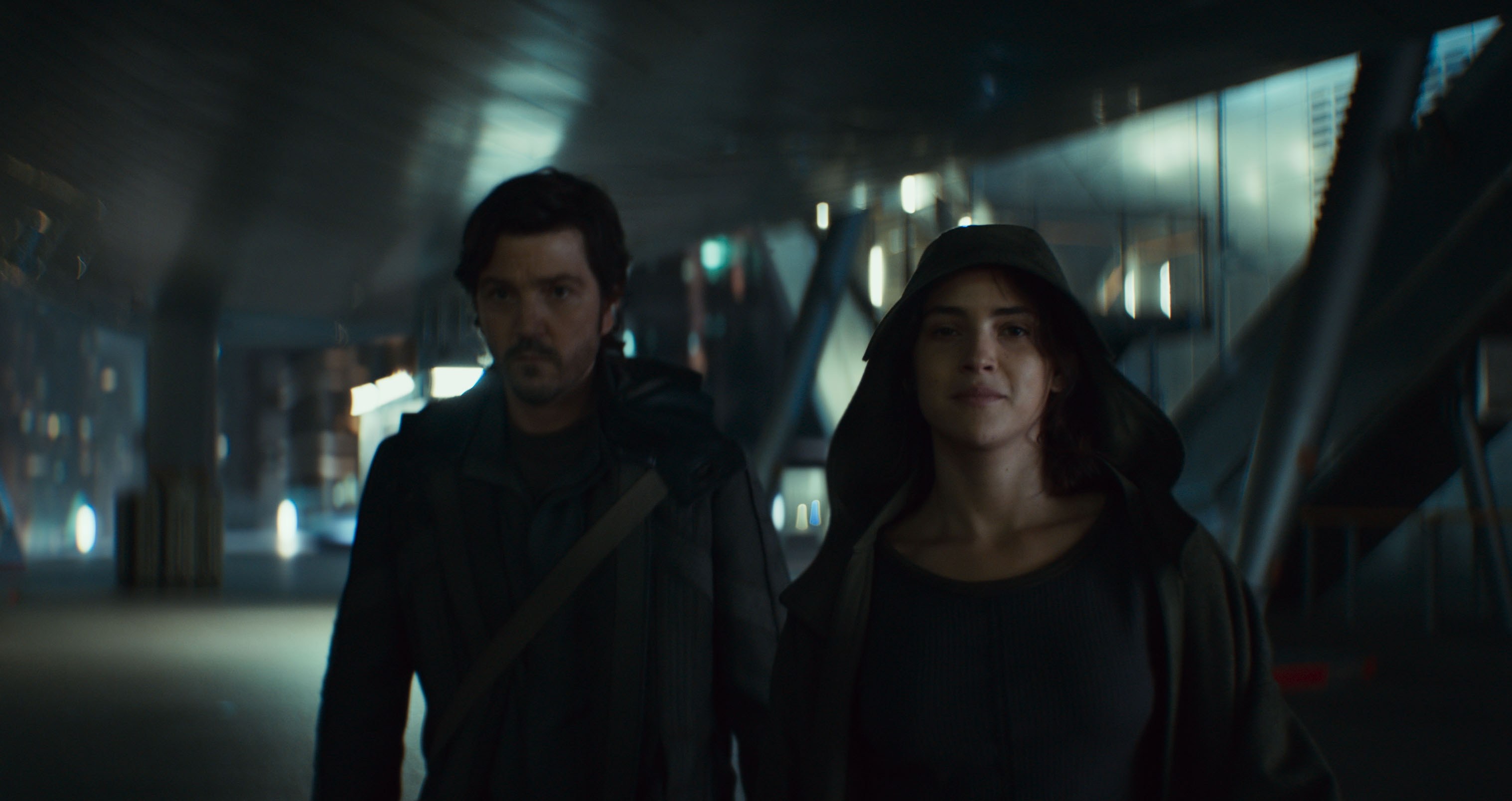 Cassian Andor (Diego Luna) and Bix Caleen (Adria Arjona), looking grimly determined, walk toward the camera in Andor season 2