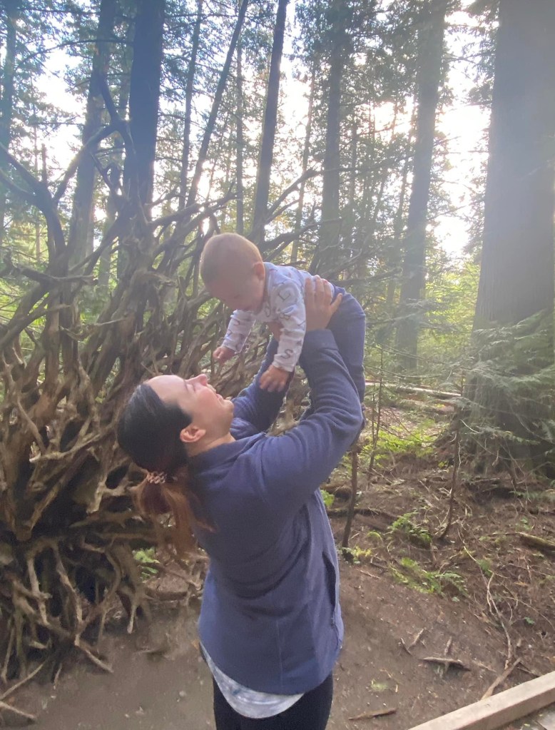 Julia Byrne holding her son Blake surrounded by tall trees. 