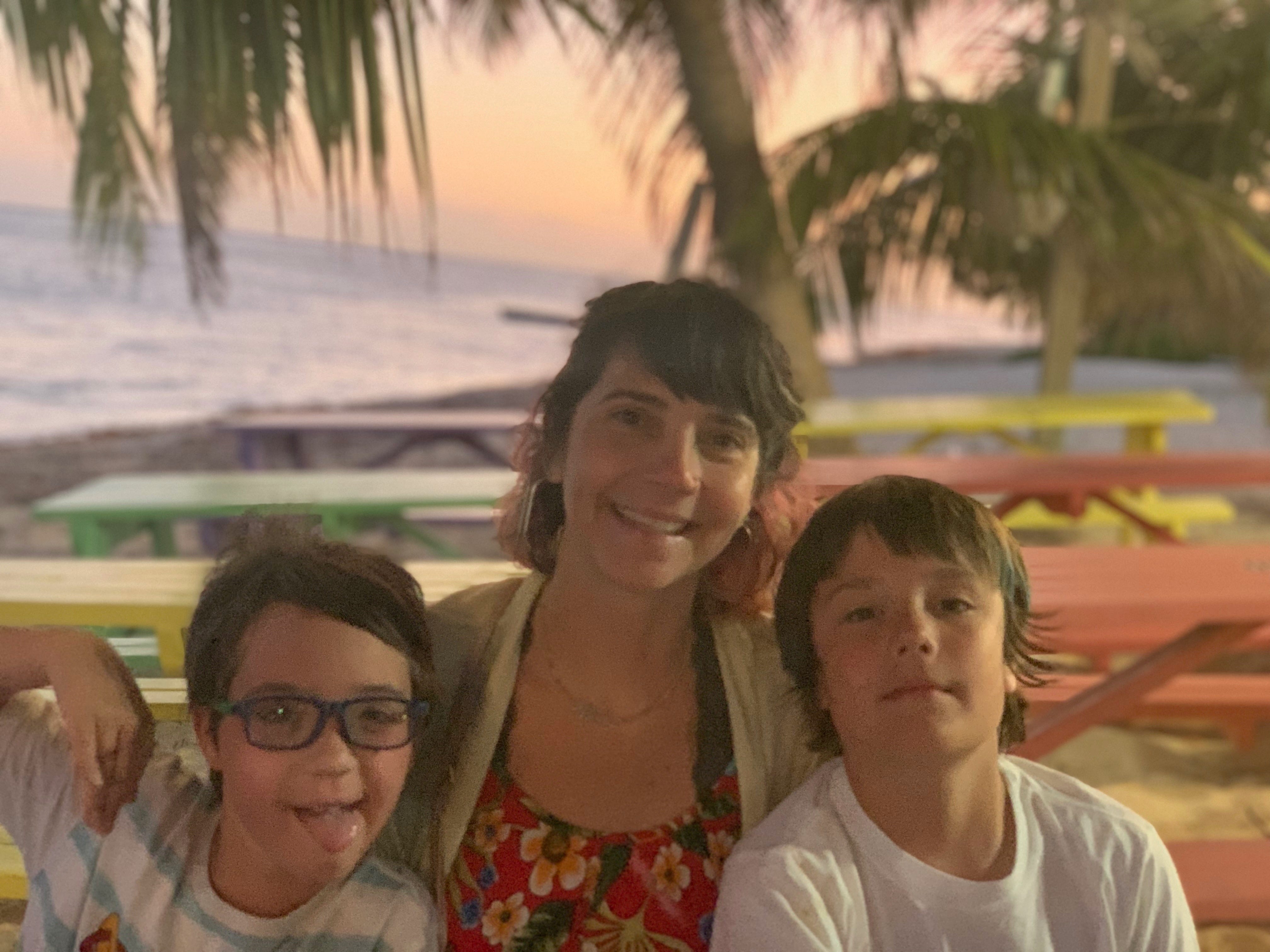 The author with two of her kids sitting on a beach by colorful picnic tables.