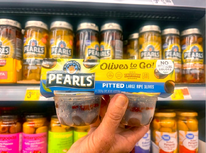 hand holding pearls olives to go pack in Walmart