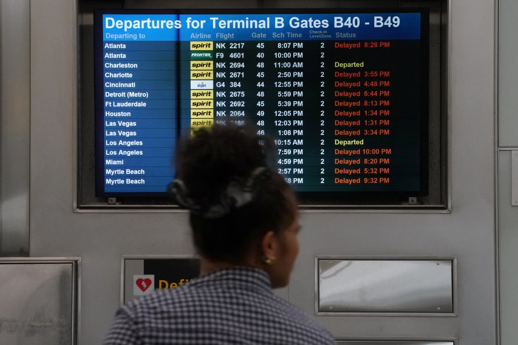 A person walks past a screen displaying delayed flights at Newark Liberty International Airport on May 9, 2025.