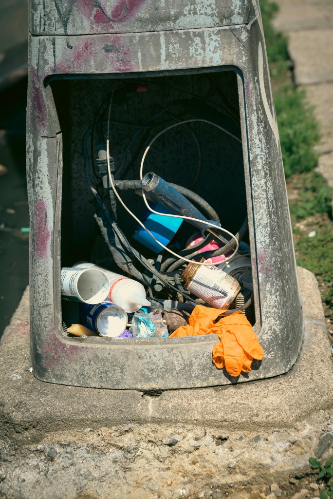 Trash tucked into a broken lamppost. 