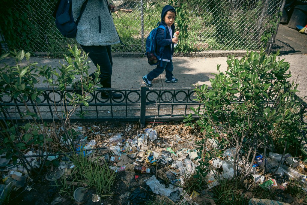 A child walks past a pile of trash in Corona, Queens.