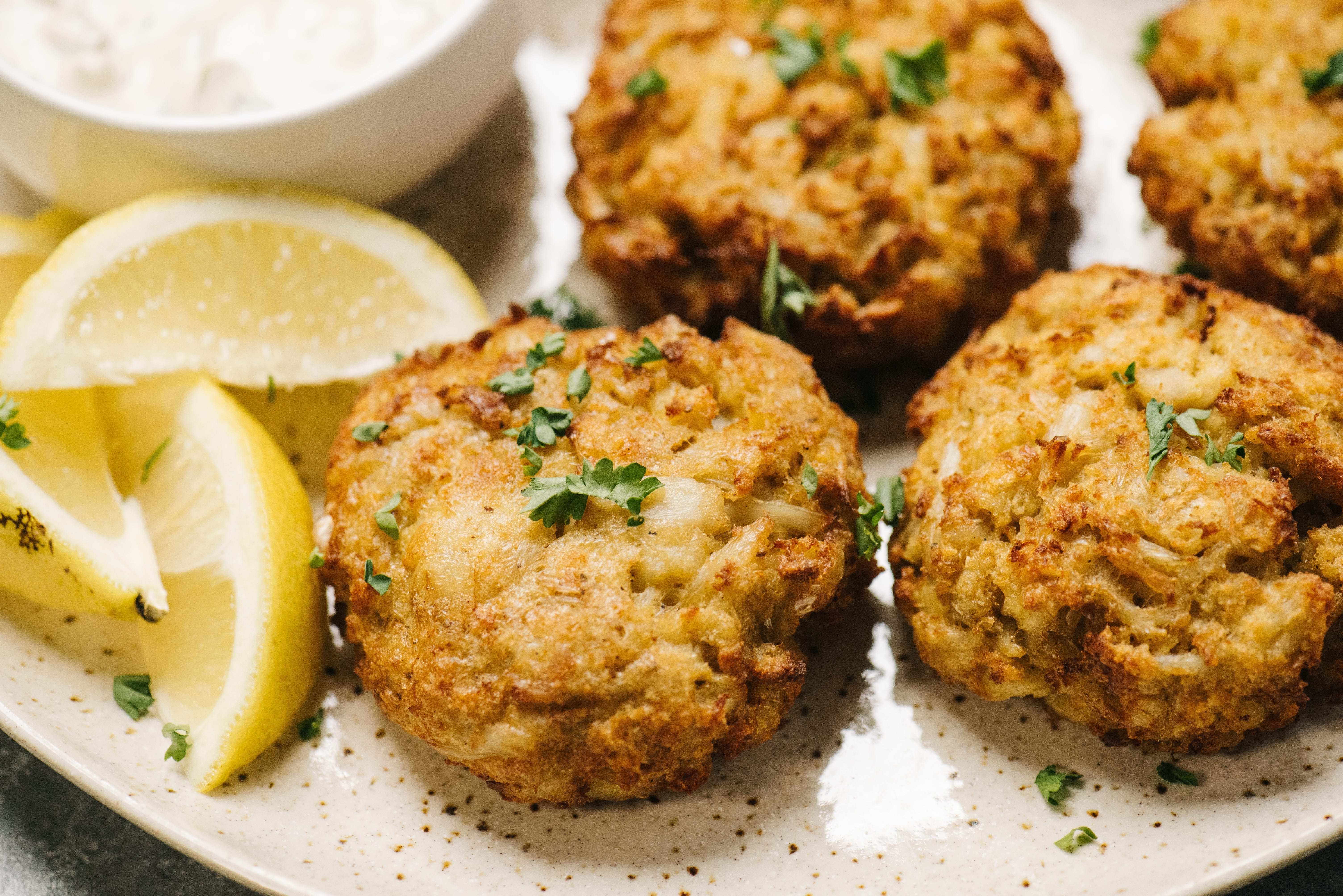 Crab cakes on plate with lemon wedges