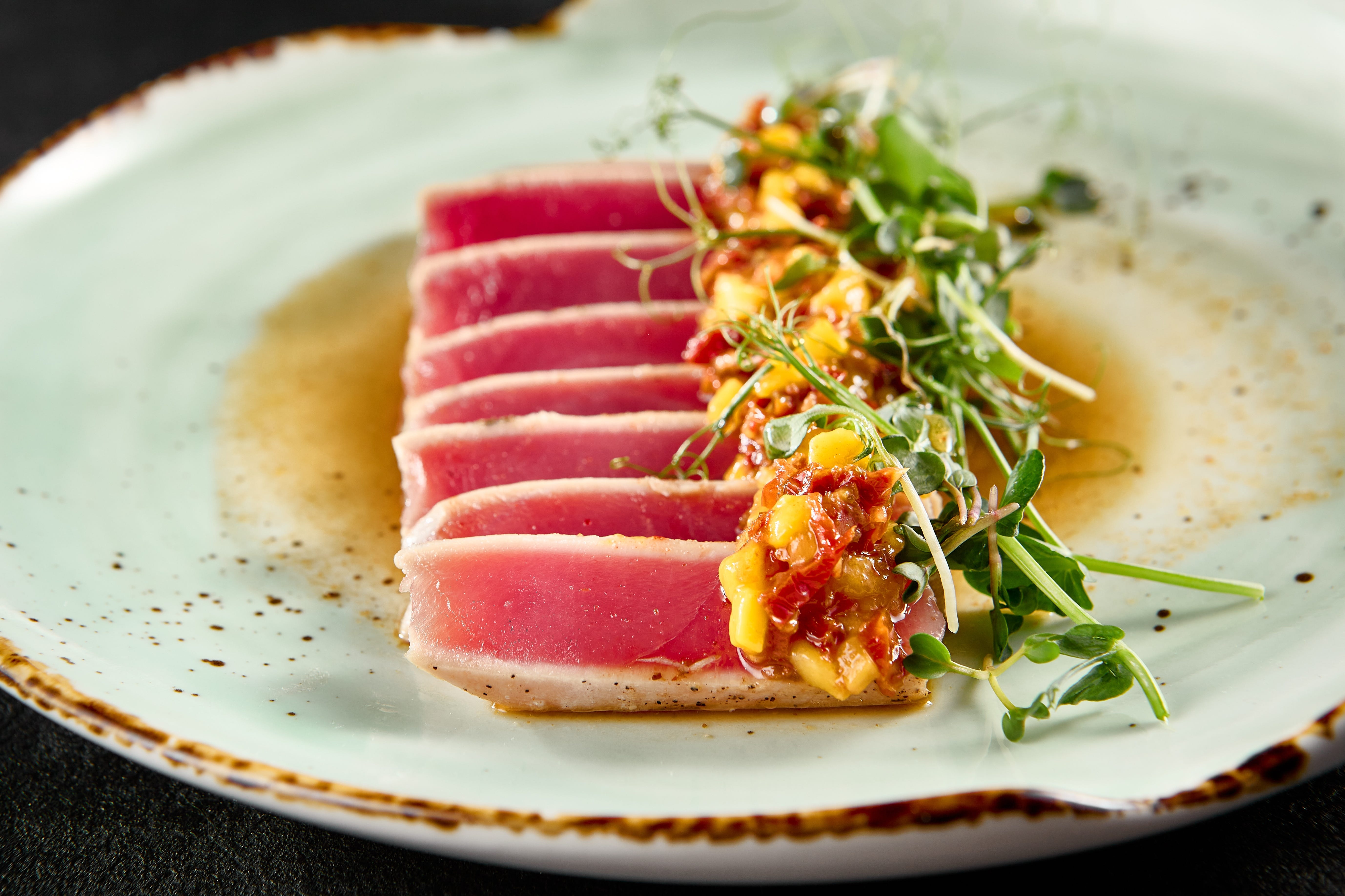 Seared tuna on plate with microgreen and chutney garnish