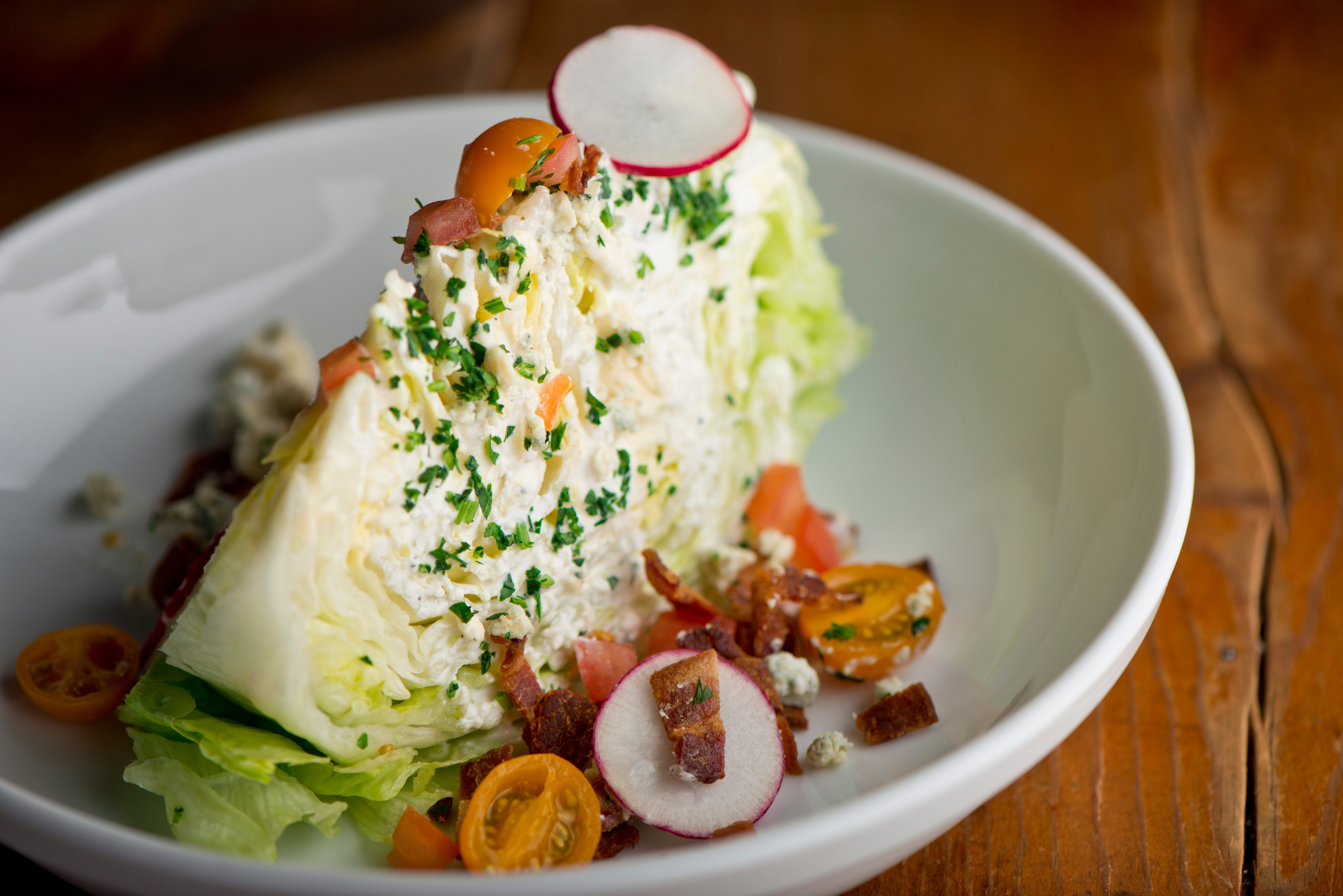 Wedge of iceberg lettuce with bacon, cheese, tomatoes, radish