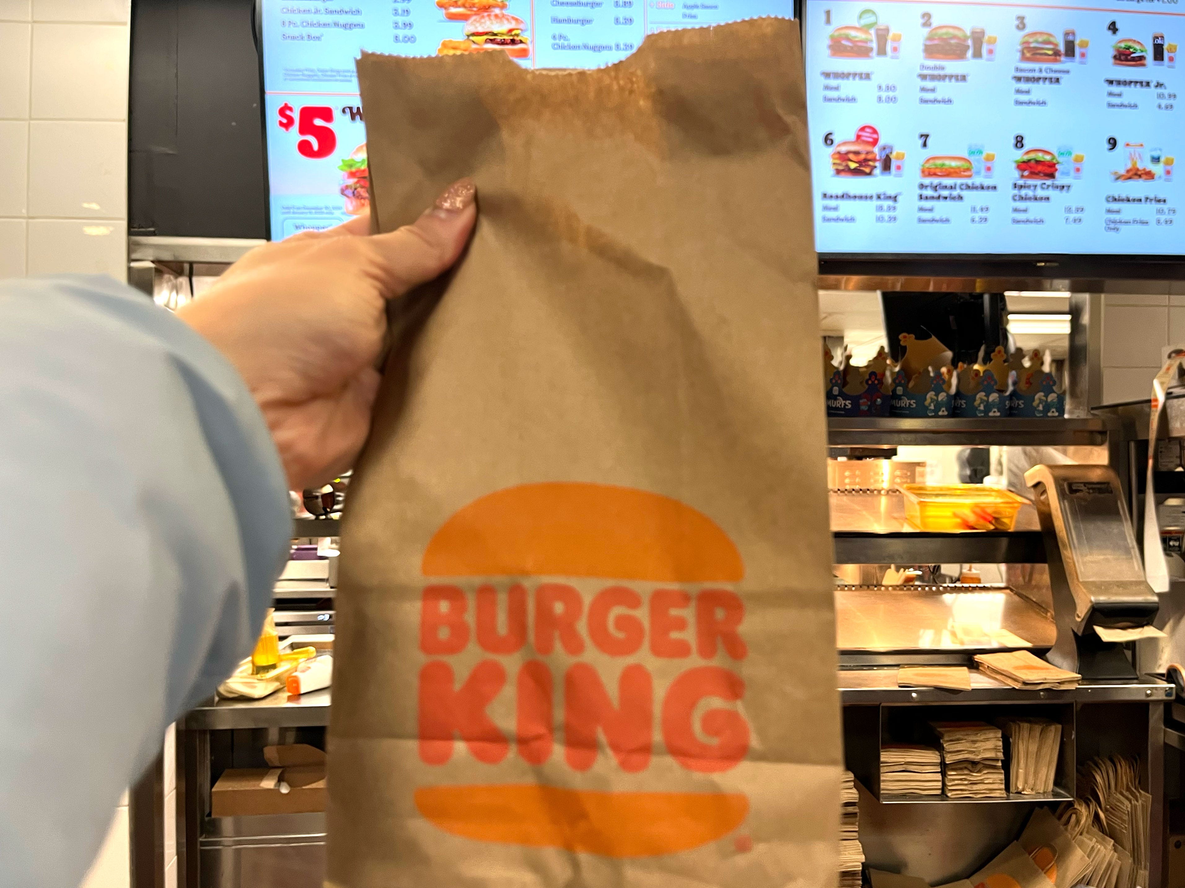 Tiffany holds a Burger King bag in front of the counter.