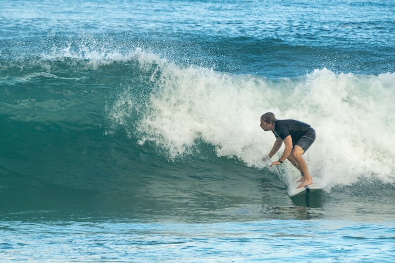 A man surfing wearing shorts