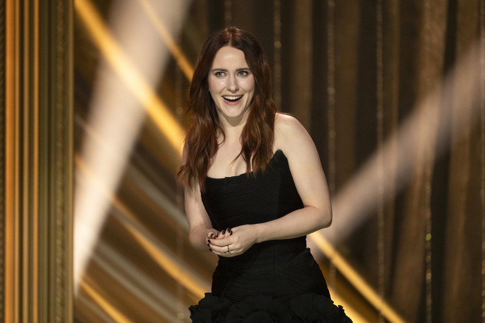 Rachel Brosnahan in a black mini dress with ruffled hem.