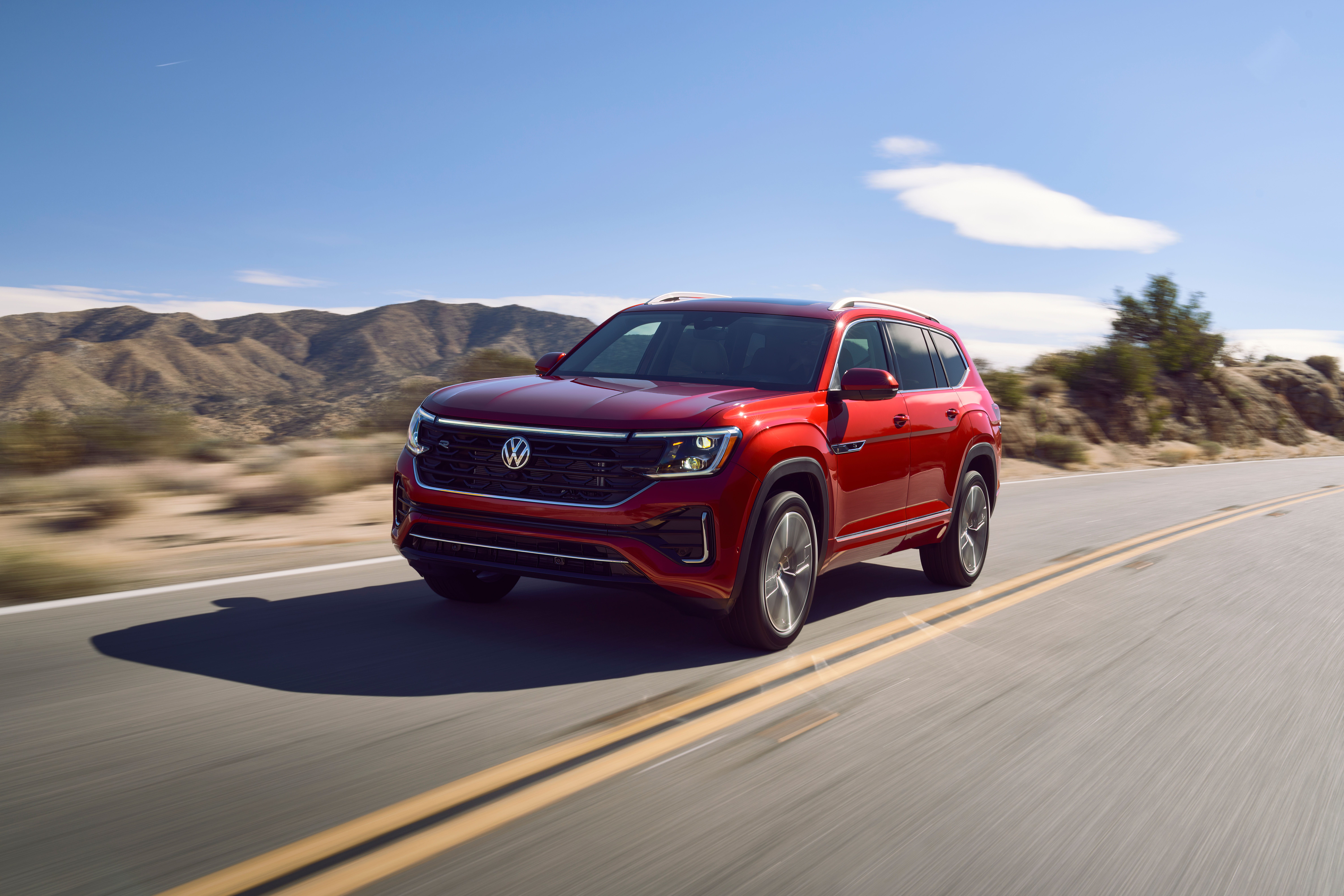 A red 2025 Volkswagen Atlas SUV driving down a road.