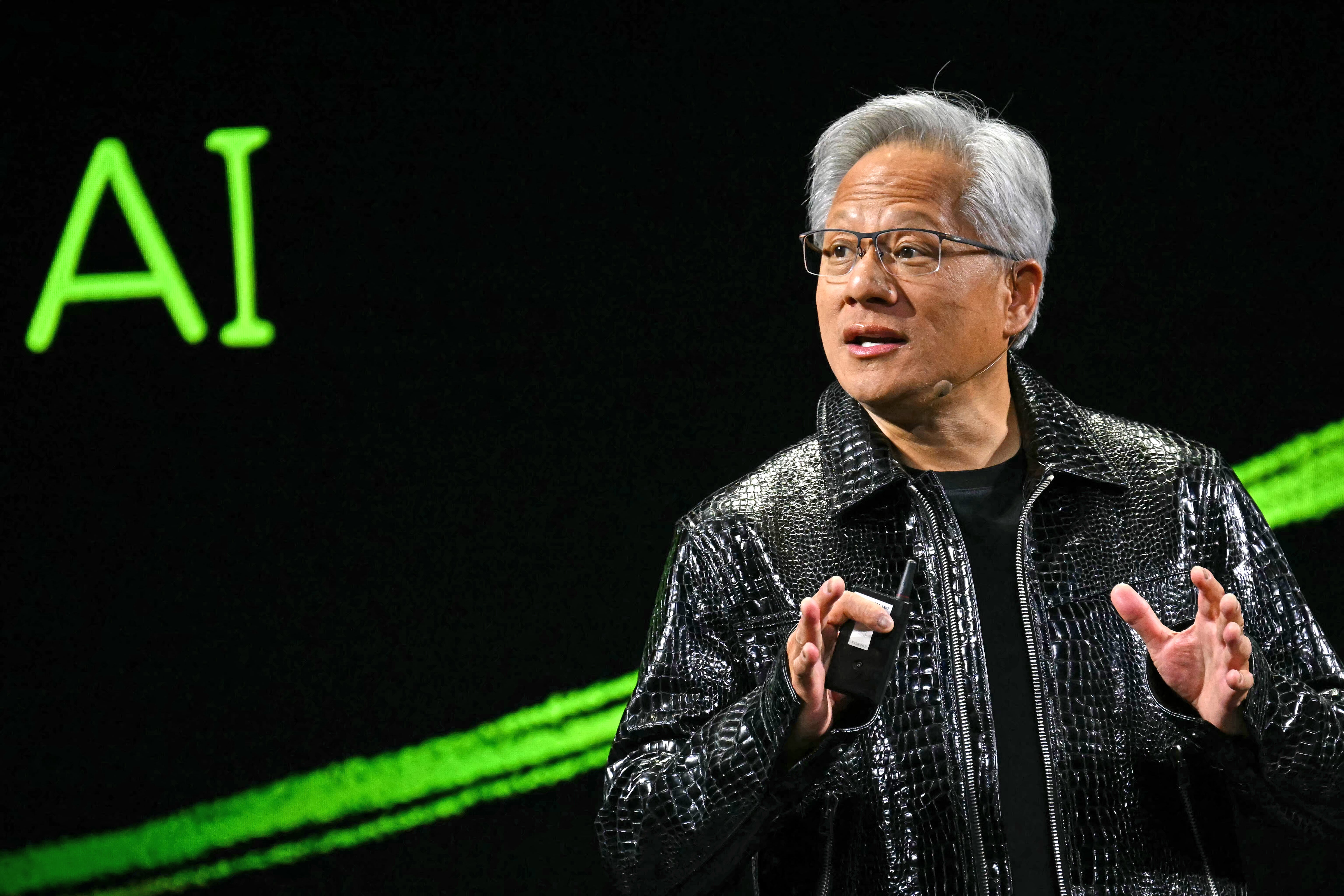 Jensen Huang wearing leather jacket, AI written on background behind him
