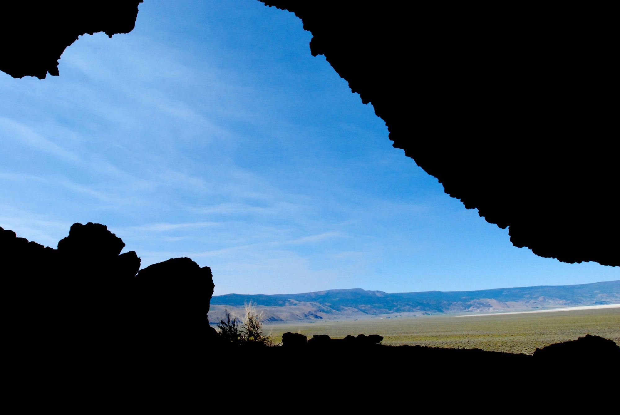 Hills and grass seen from inside a dark cave